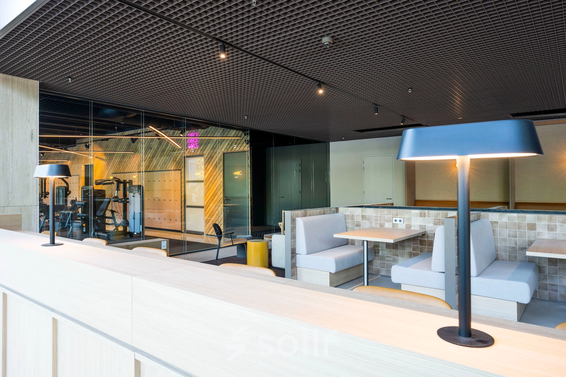 Modern office space for rent at Nachtwachtlaan 20, Amsterdam West, featuring stylish booth seating and a gym area.