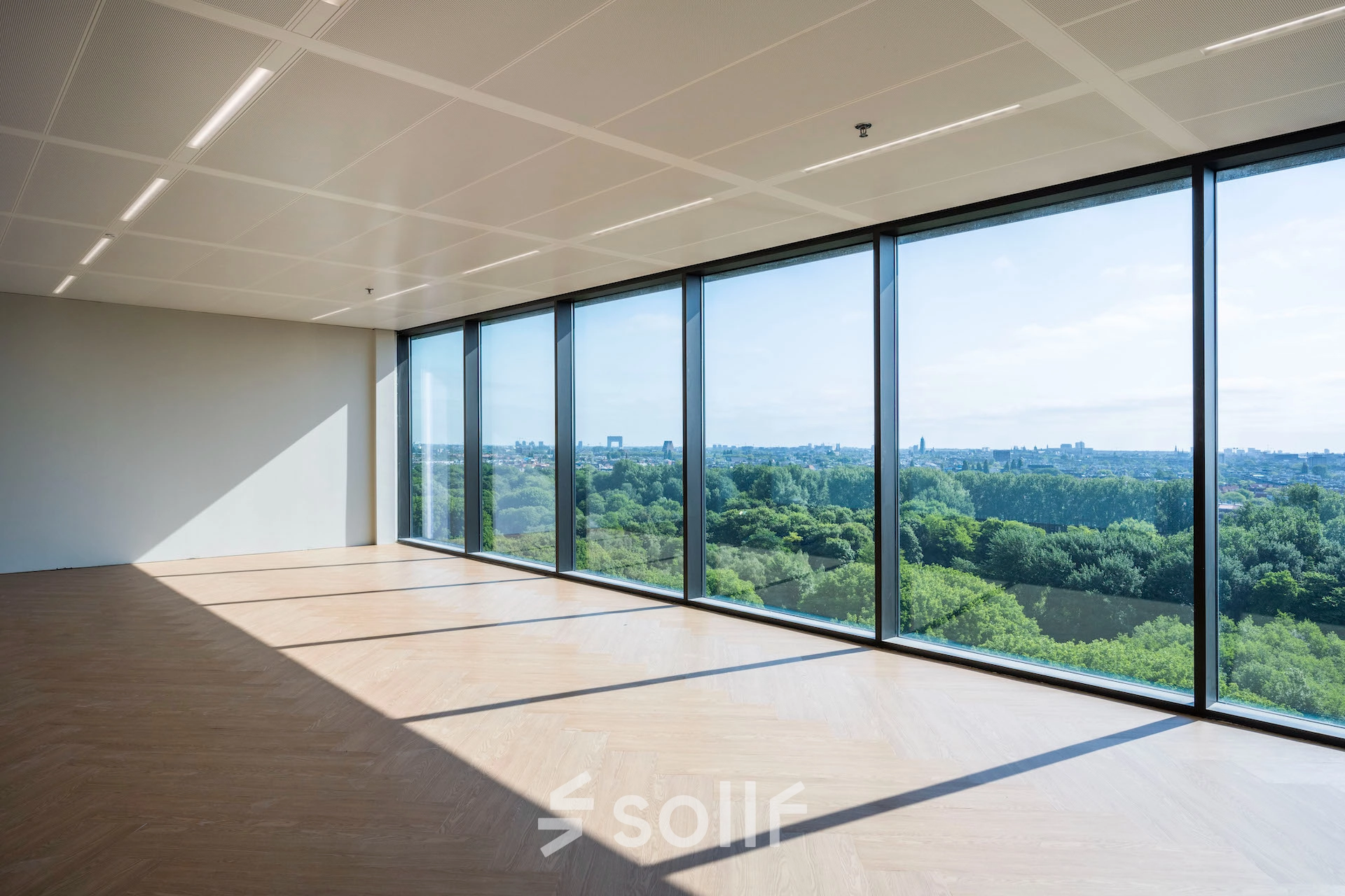 Spacious office area with large windows offering a panoramic view of greenery in Amsterdam West, perfect for office space rental.