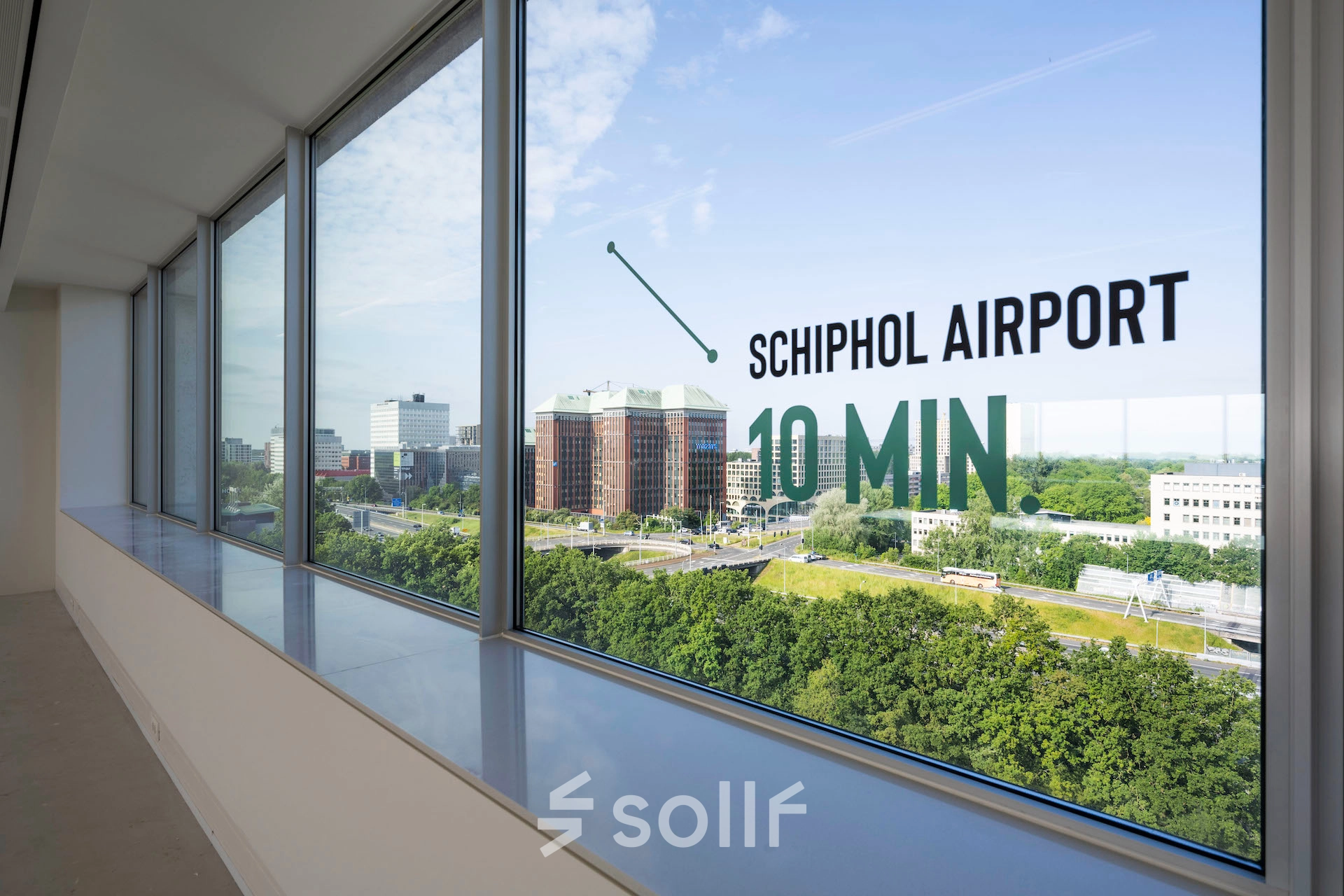 Large windows overlooking green space and nearby buildings at an office to rent in Amsterdam West.
