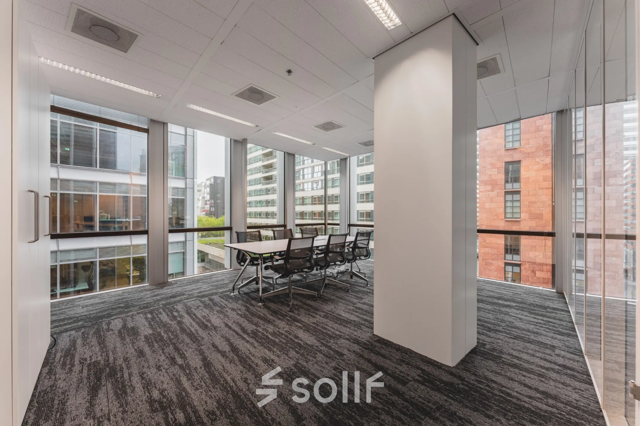 Bright office space with large windows and a meeting table, available for rent at Claude Debussylaan 10, Amsterdam Zuidas.