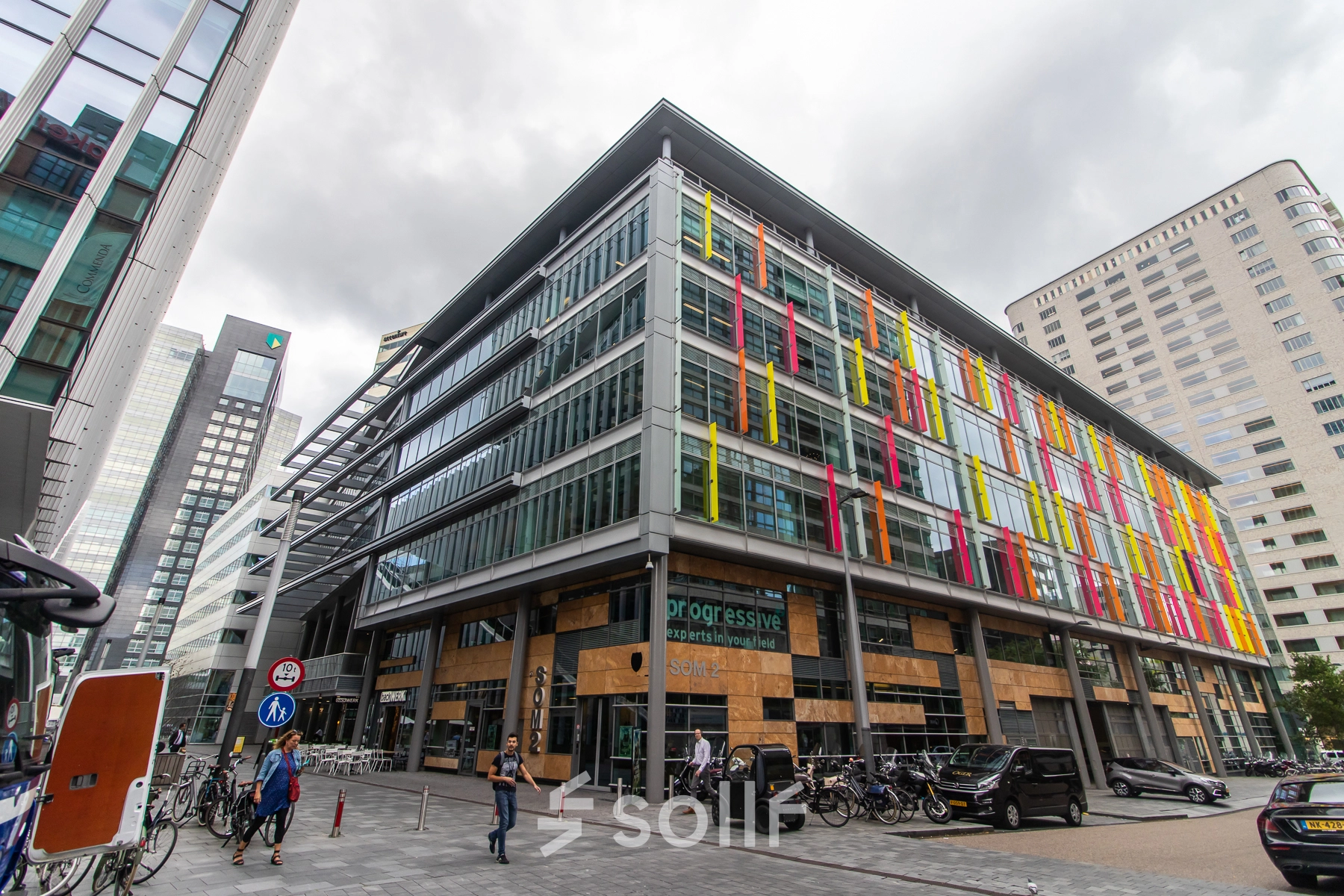 Exterior view of the office building at Claude Debussylaan 7-29, Amsterdam Zuidas, showcasing colorful facades and bicycles nearby, ideal for office space rental.