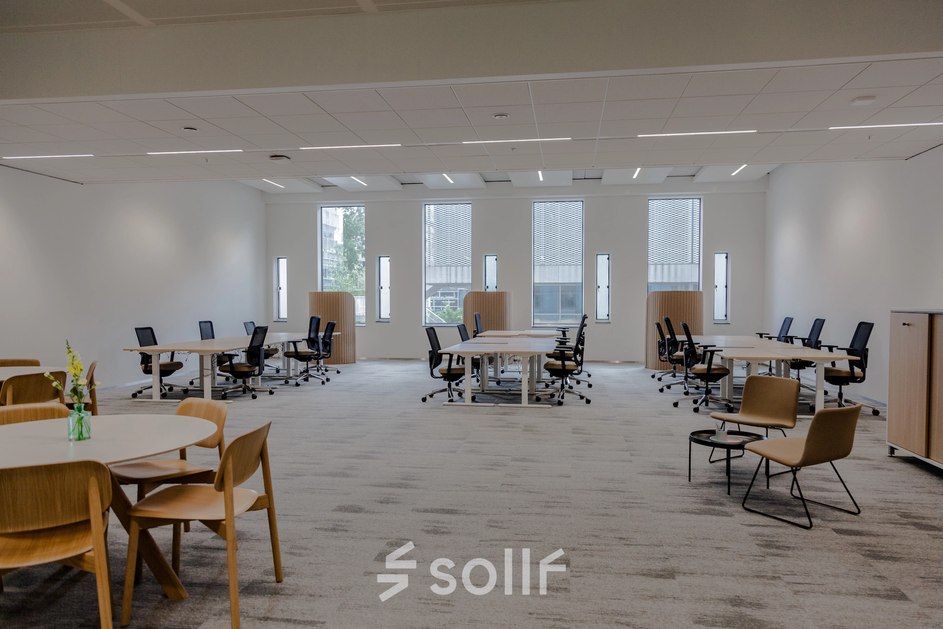 Spacious furnished office space rental at Fred. Roeskestraat 100, Amsterdam Zuidas, featuring multiple desks and chairs with large windows providing natural light. Ideal office to rent for collaborative work.