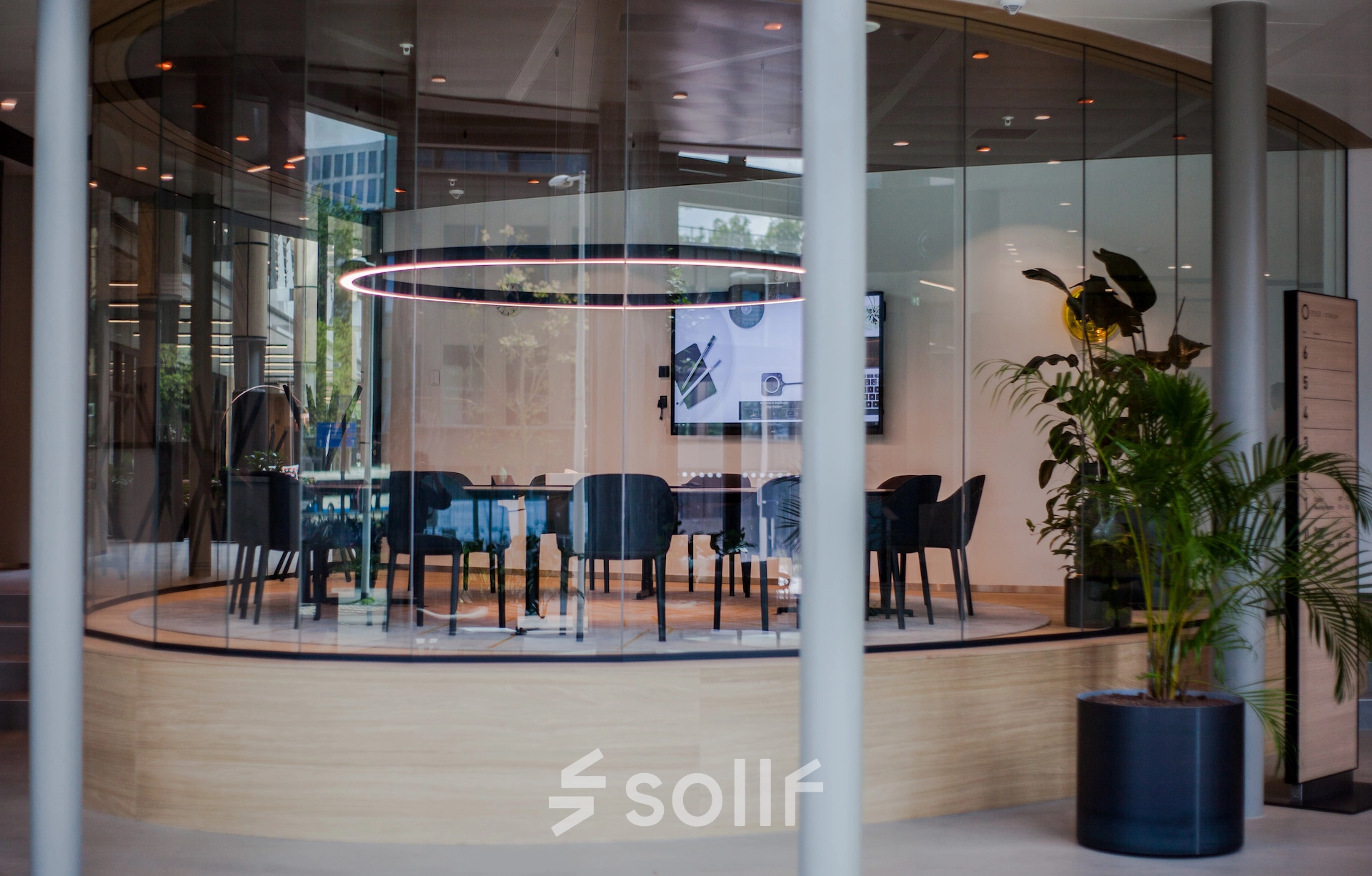 Modern conference room with a circular table and sleek chairs, set in a glass enclosure at Fred. Roeskestraat 100, ideal for office space rental in Amsterdam Zuidas.