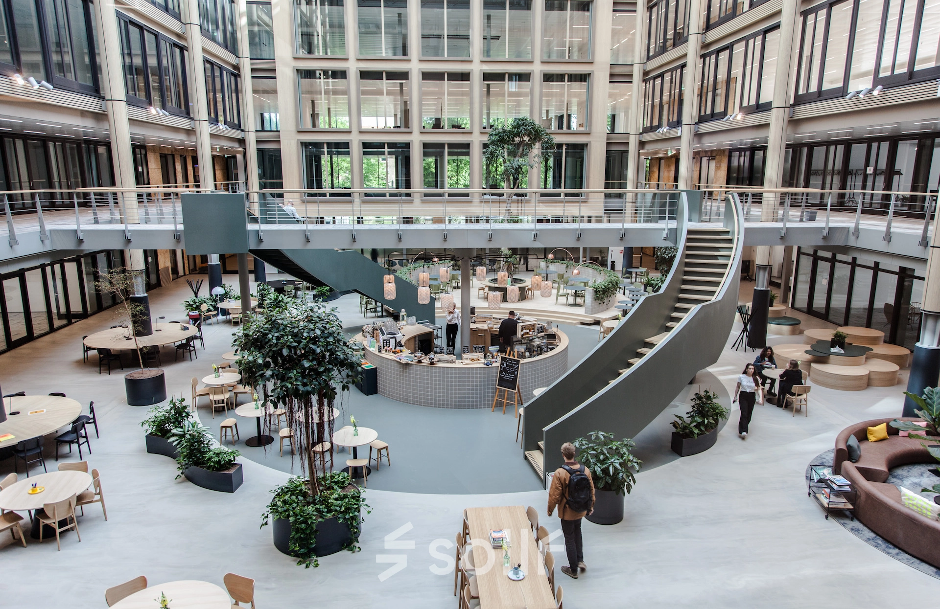 Spacious interior at Fred. Roeskestraat 100, Amsterdam Zuidas, showcasing an open floorplan with modern furnishings and individuals engaging in discussions and activities. Ideal for office space rental.