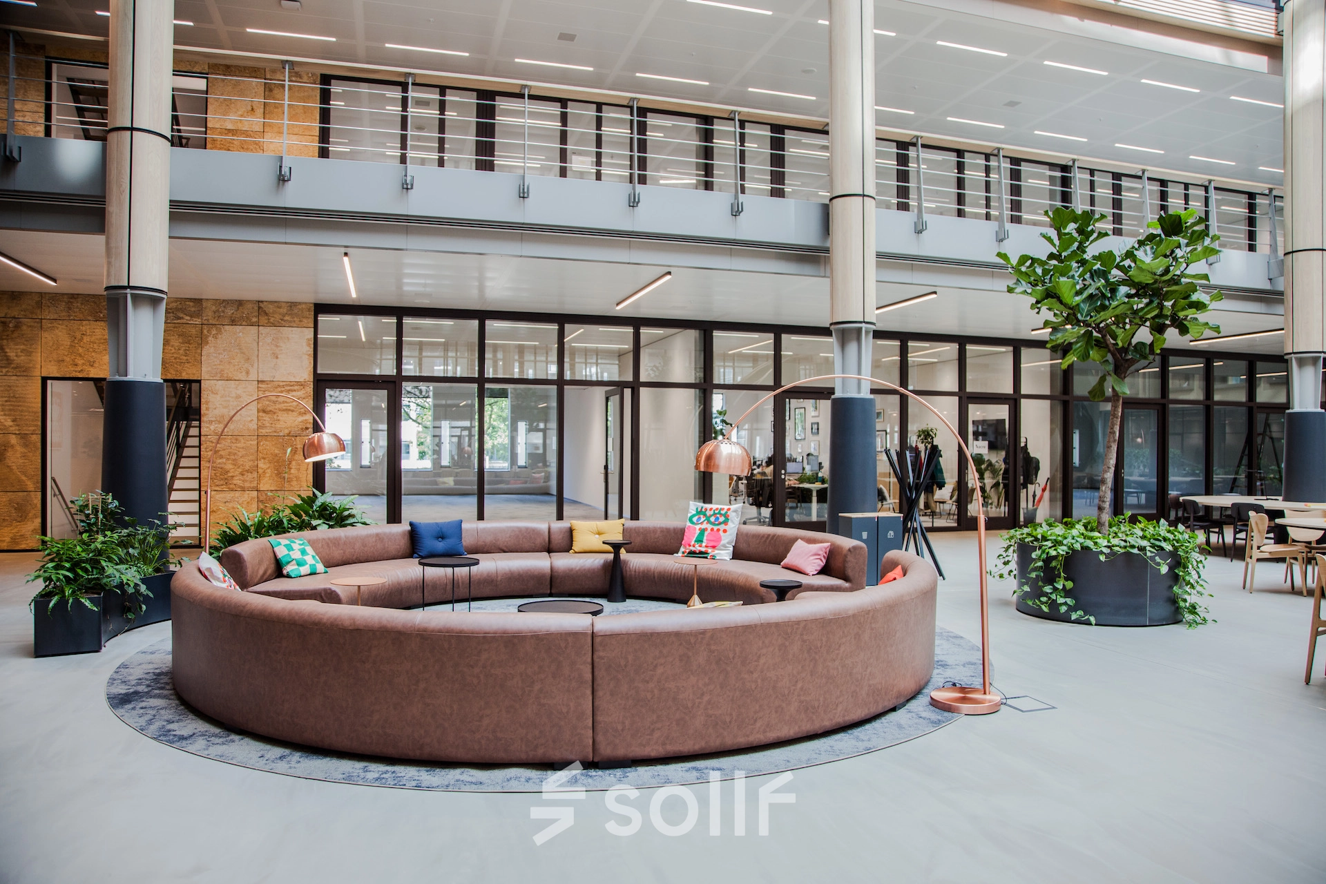 Spacious office lounge area with circular seating and plants at Fred. Roeskestraat 100, ideal for office space rental in Amsterdam Zuidas.