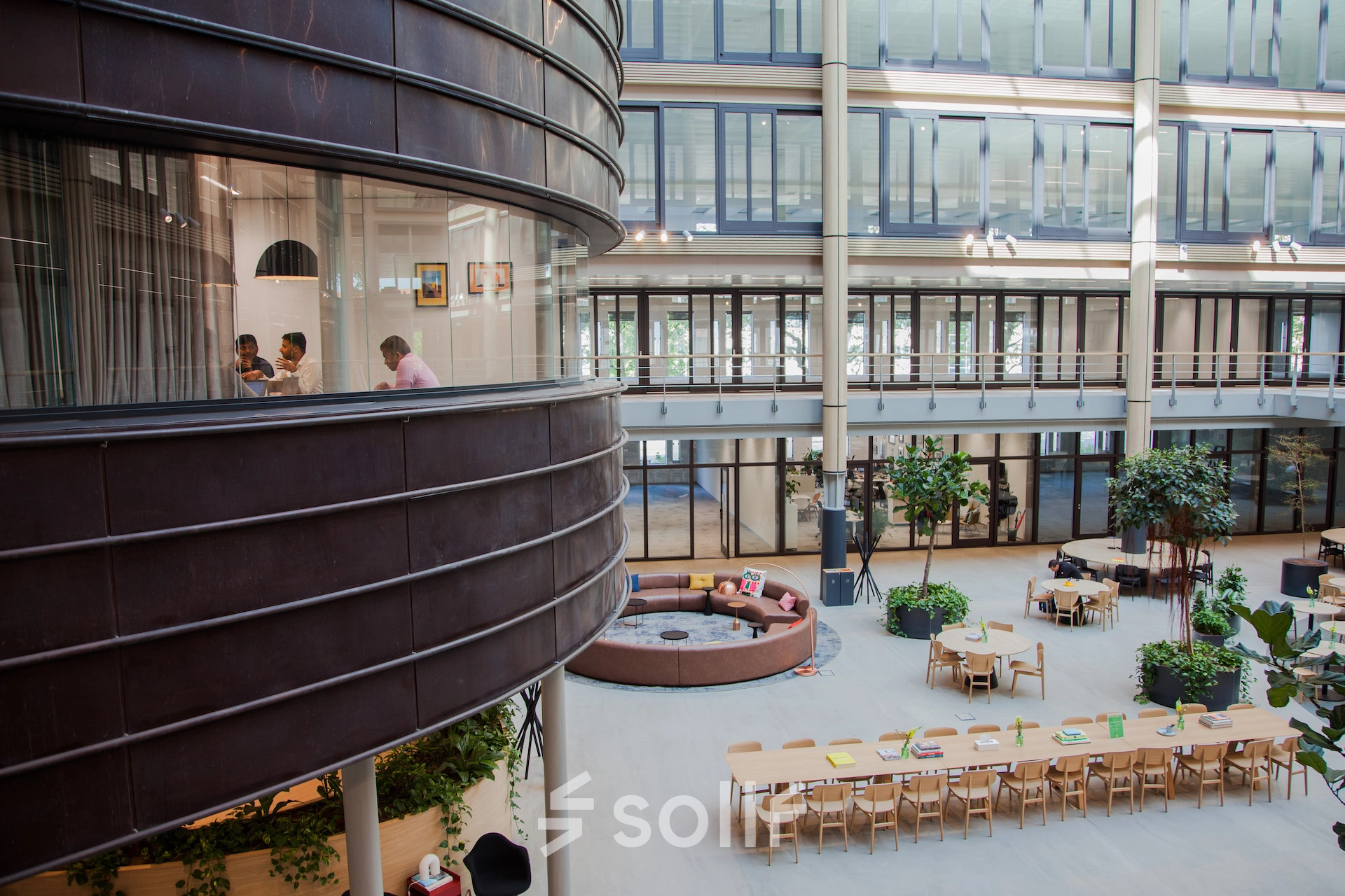 Spacious office at Fred. Roeskestraat 100, Amsterdam Zuidas, with people engaged in a meeting, showcasing modern office space rental options.