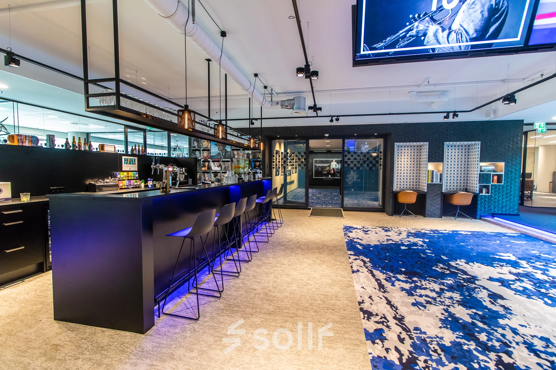 Modern office space for rent at Gustav Mahlerplein 28 & 58-60, Amsterdam Zuidas, featuring a stylish bar area with high stools and a vibrant carpet.