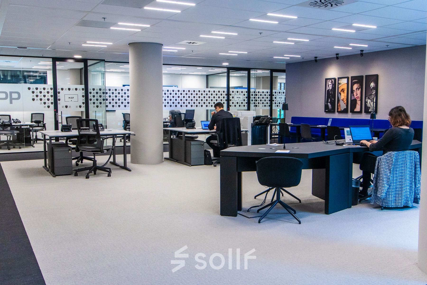 Modern office space rental at Gustav Mahlerplein in Amsterdam Zuidas with people working on laptops at desks, featuring open workspaces with contemporary furniture.