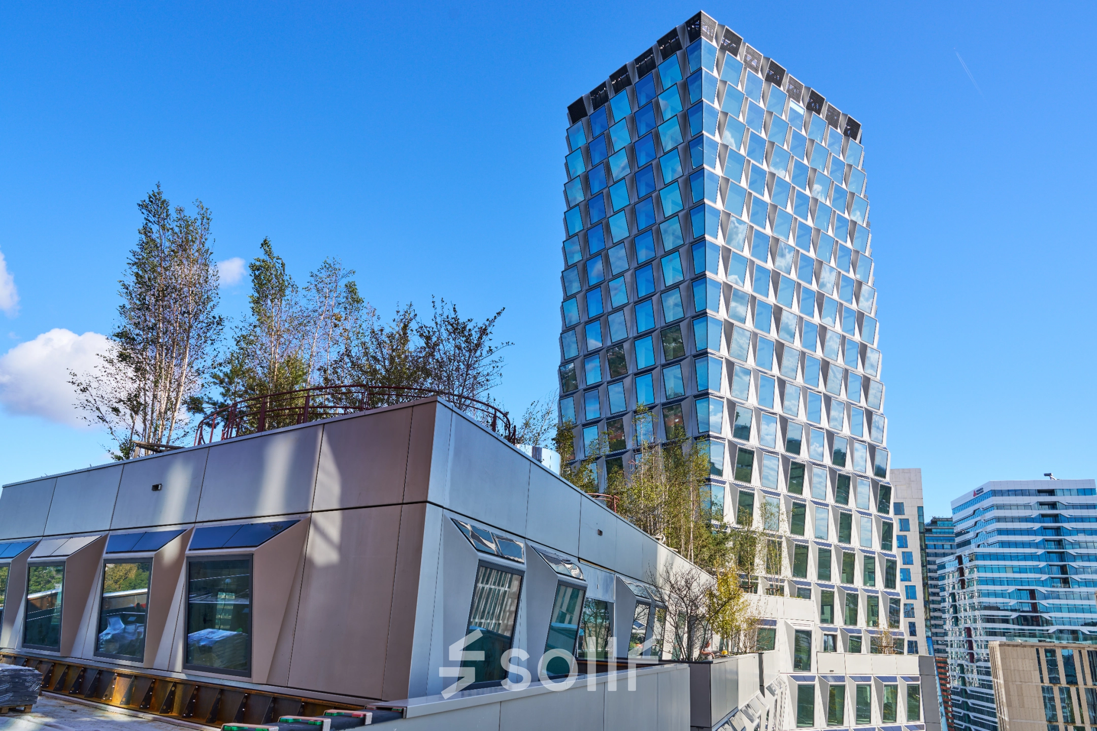 Exterior view of a modern office building at Hildegard Von Bingenstraat 44, Amsterdam Zuidas, with a unique facade and rooftop greenery. Ideal for those seeking office space rental in a vibrant location.