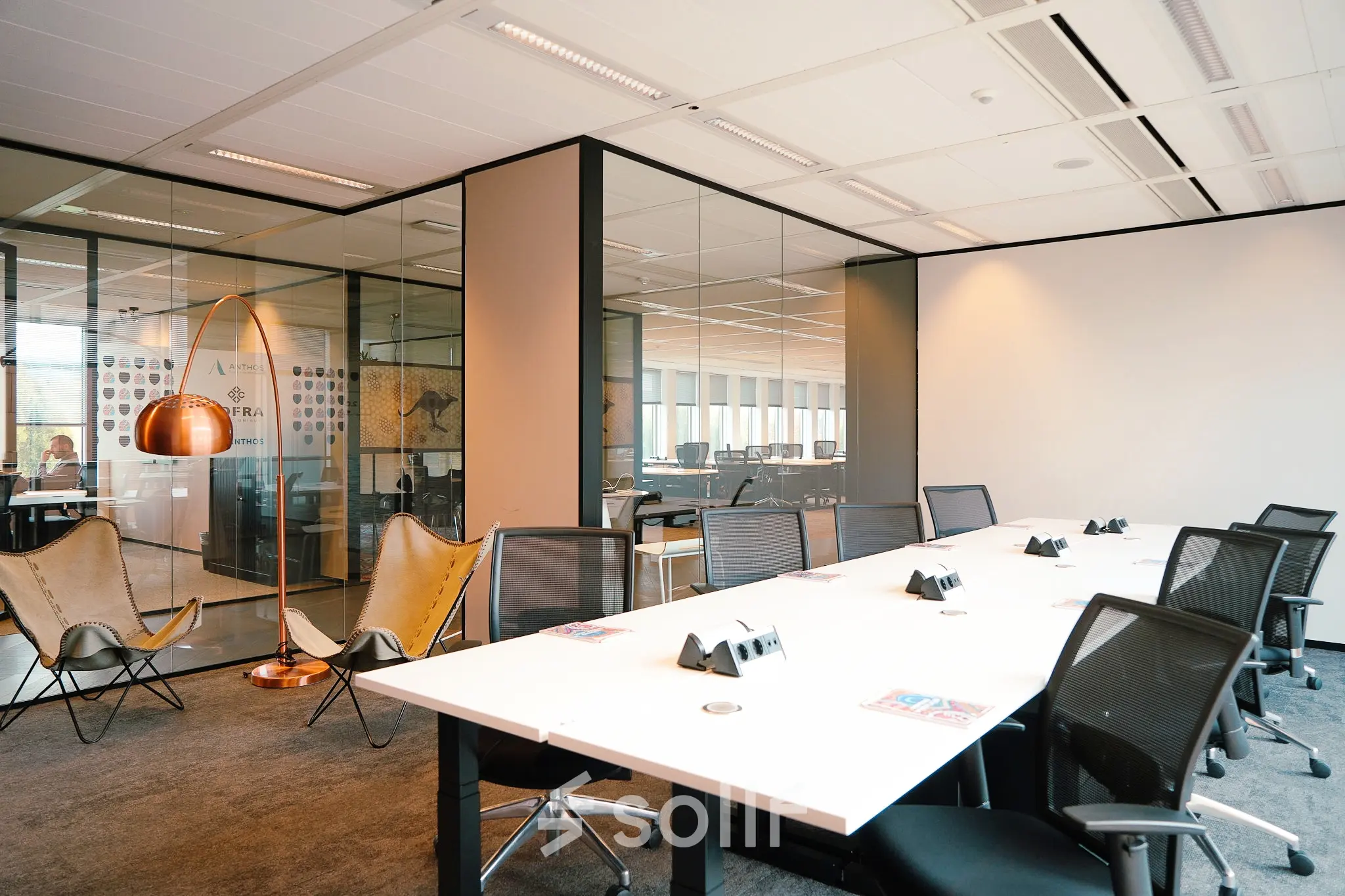 Modern office space in Amsterdam Zuidas with large conference table, comfortable chairs, and glass walls. Ideal for office space rental at Jachthavenweg 109.