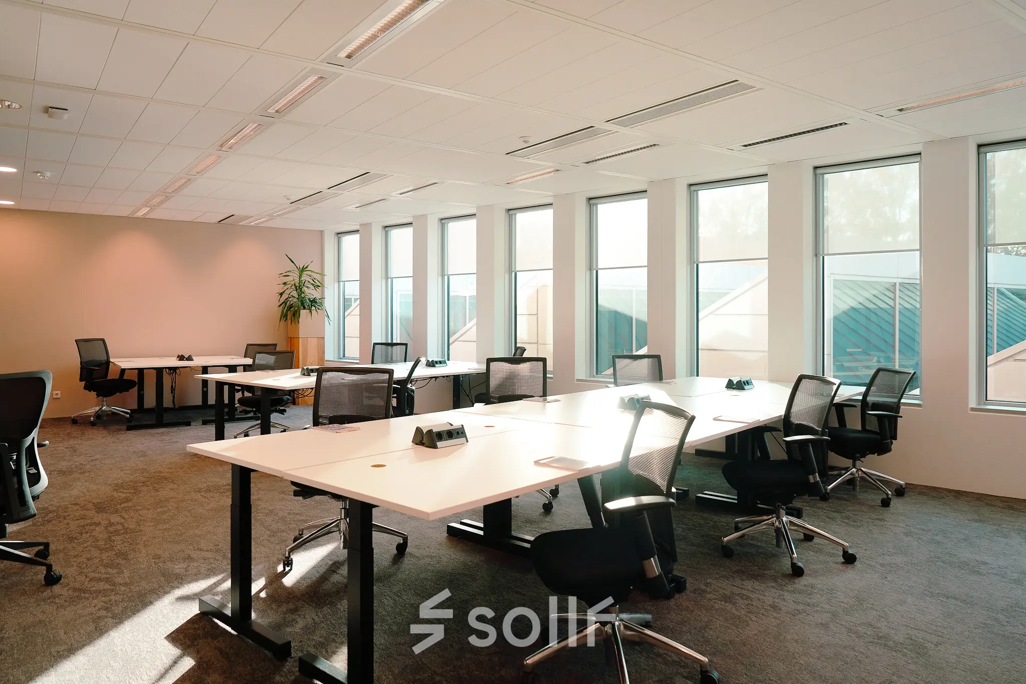 Bright and airy office space available for rent at Jachthavenweg 109, Amsterdam Zuidas, featuring multiple workstations with ergonomic chairs and large windows for natural light.
