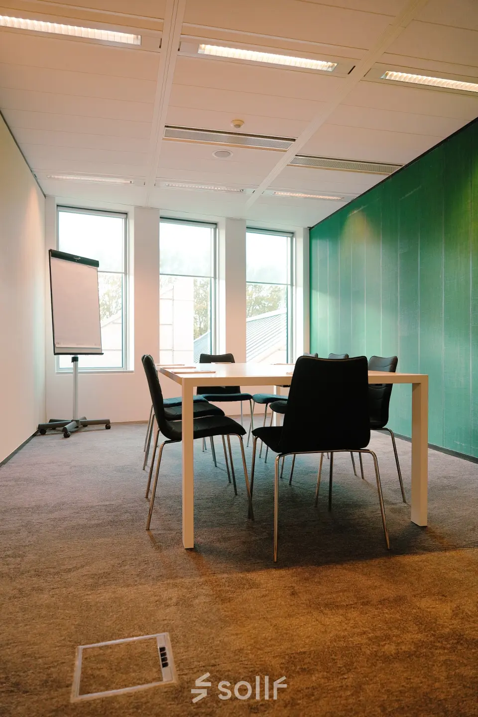 Well-lit office space at Jachthavenweg 109, Amsterdam Zuidas, featuring a table and chairs, ideal for meetings. Perfect for anyone seeking office space rental in a professional setting.