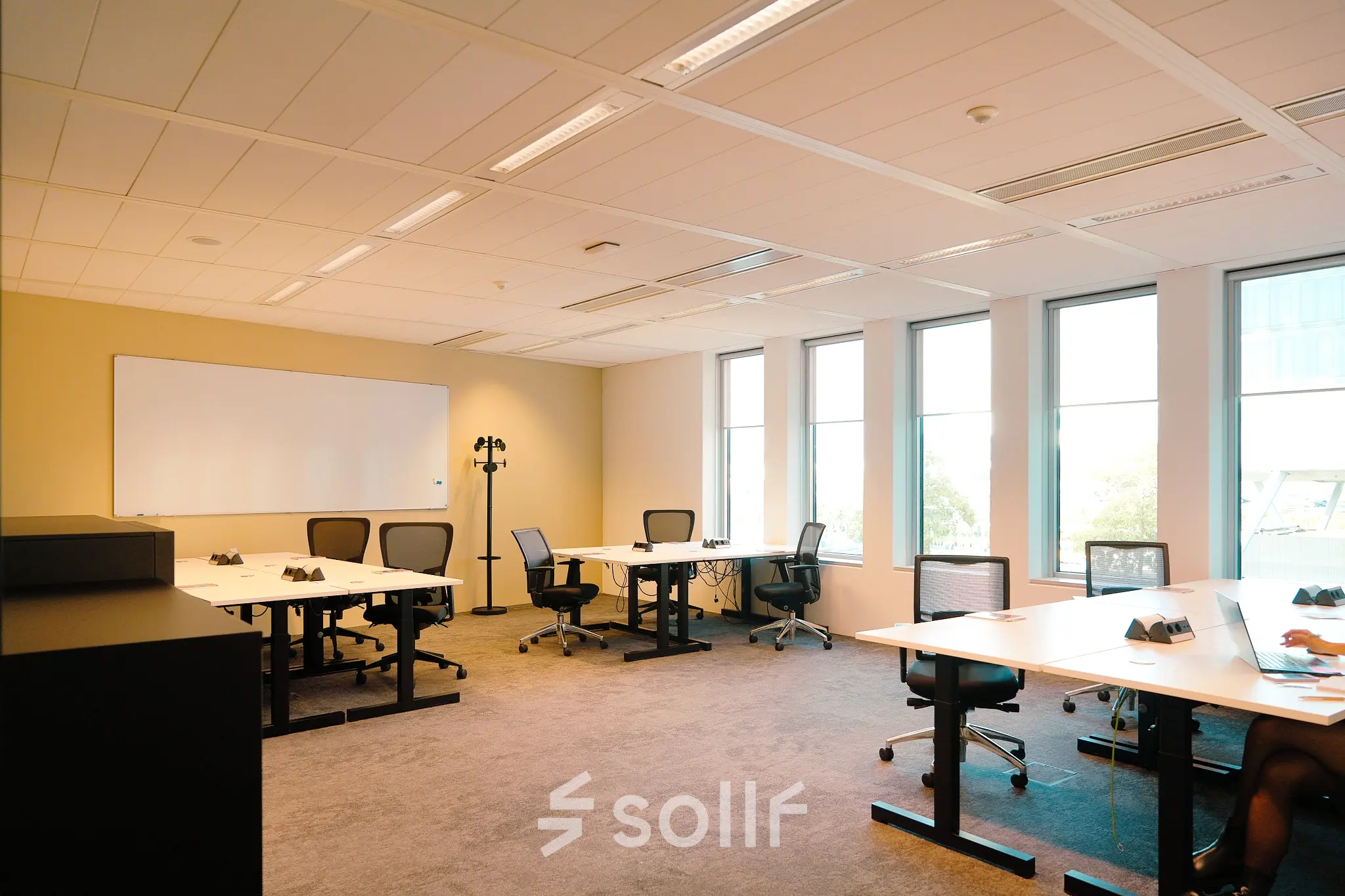 Furnished office space with several desks and chairs, well-lit by natural light, ideal for rent at Jachthavenweg 109 in Amsterdam Zuidas.