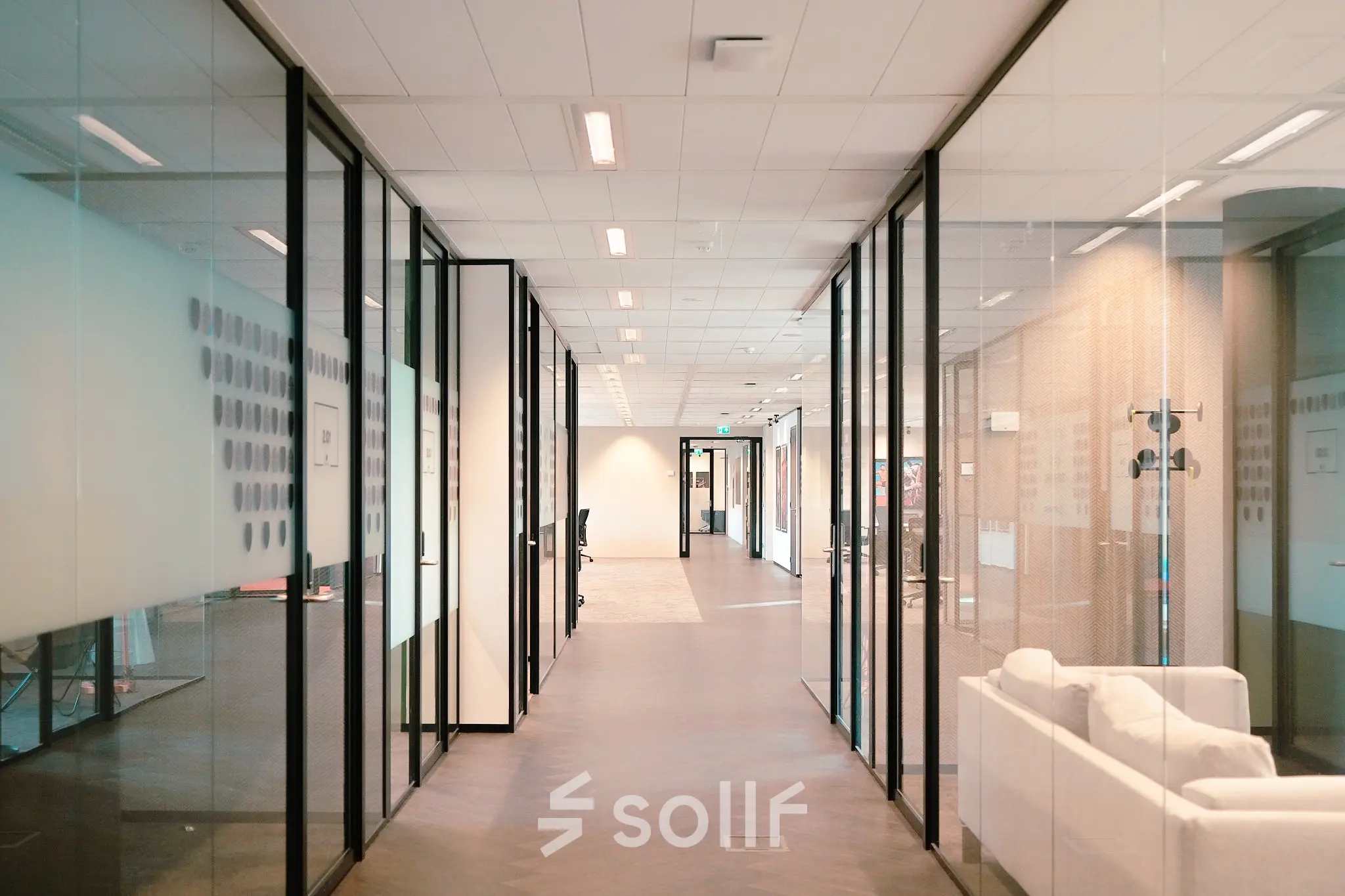 Modern office interior at Jachthavenweg 109, Amsterdam Zuidas, featuring glass-walled corridors ideal for office space rental.