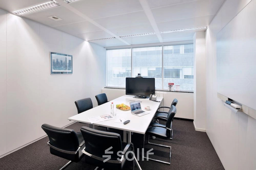 Modern conference room available for office space rental at Lange Lozanastraat 142, Antwerp Center, featuring a sleek table, black chairs, and a large screen.