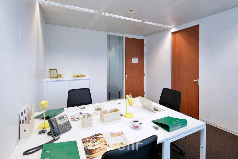Interior office space at Lange Lozanastraat 142, Antwerp Center, featuring a furnished workspace with a white table, office chairs, and various desk items ideal for office space rental.