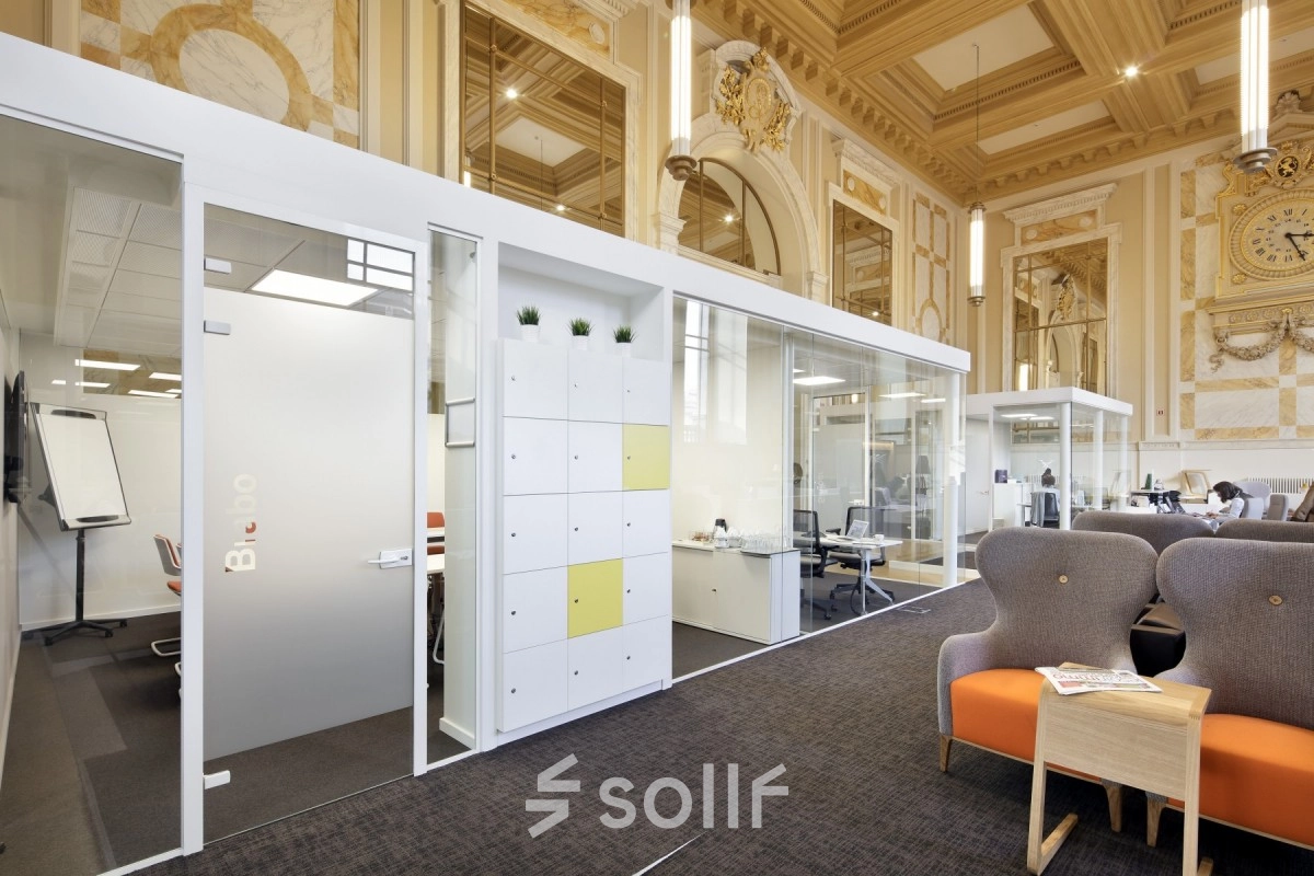 Elegant office space rental at Pelikaanstraat 3, Antwerp Center with glass-partitioned workspaces and comfortable seating.