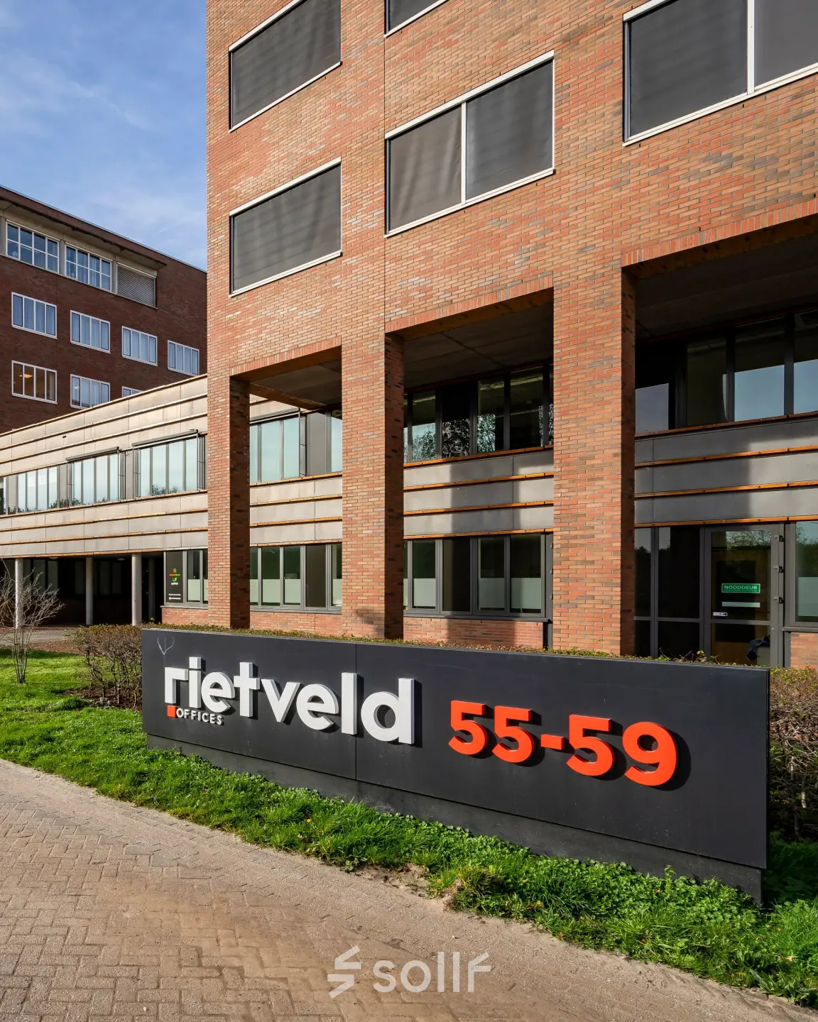 Exterior view of an office building at Het Rietveld 55-59 in Apeldoorn, featuring a modern facade with a prominent sign. Potential office space rental location.