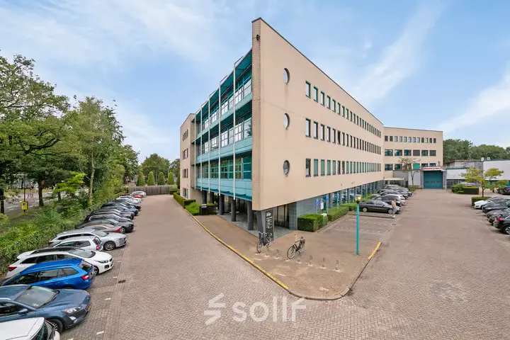 Exterior view of office space for rent at Lange Amerikaweg 55-61, Apeldoorn, featuring a large modern building with ample parking.