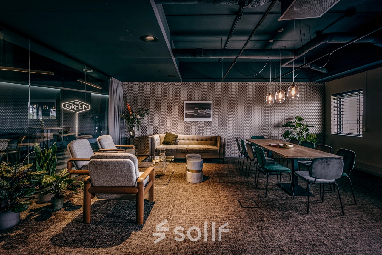 Stylish office space available for rent at Lange Amerikaweg 55-61, Apeldoorn, featuring a furnished area with modern seating and a large meeting table.
