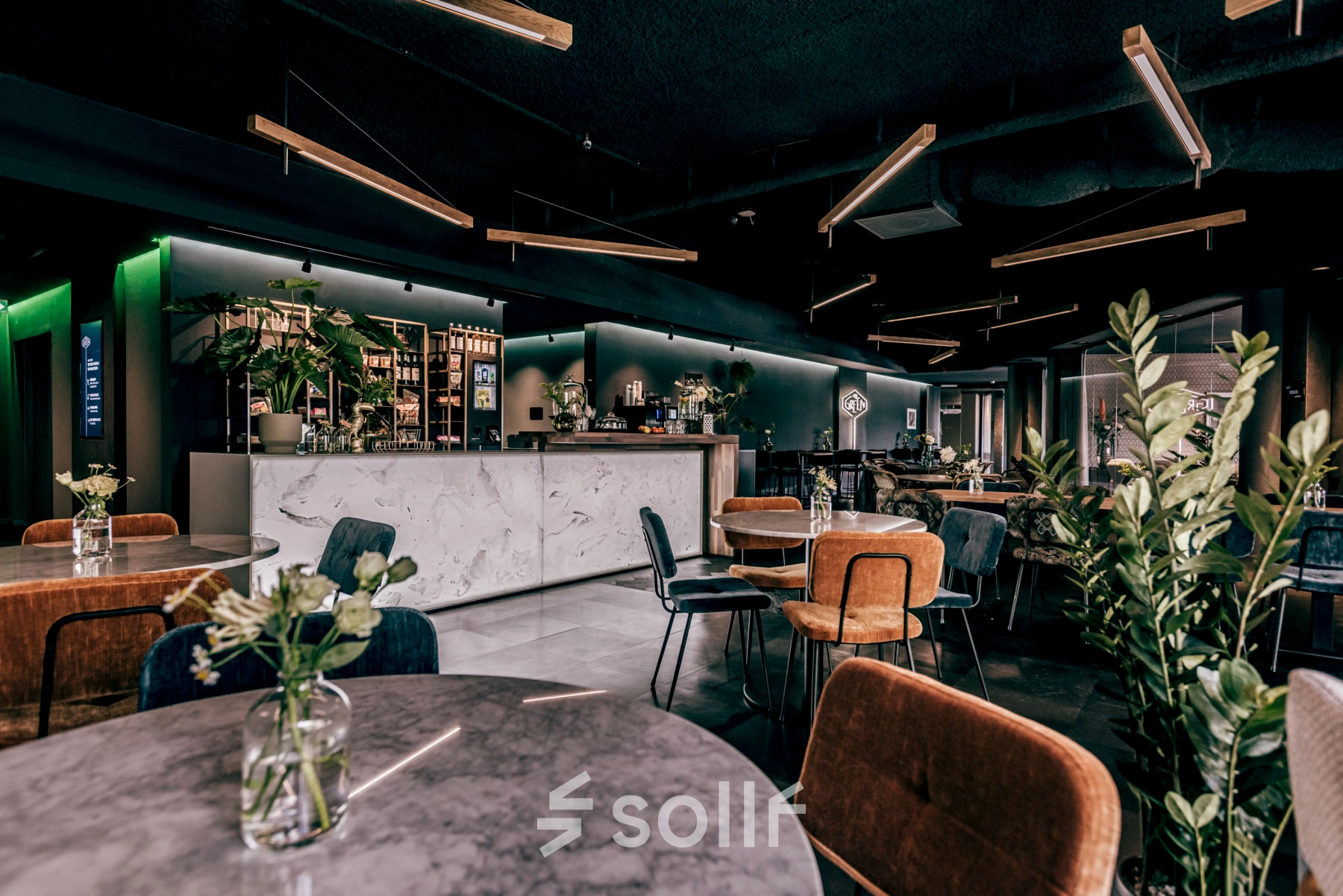 Stylish office space in Apeldoorn with modern furnishings, including round tables, chairs, and plants. Suitable for rent office space or office space rental.