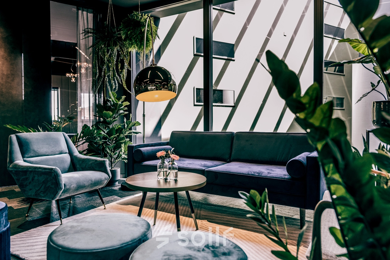 Modern and stylish office lounge at Lange Amerikaweg 55-61 in Apeldoorn, featuring comfy seating and vibrant plants, ideal for office space rental.