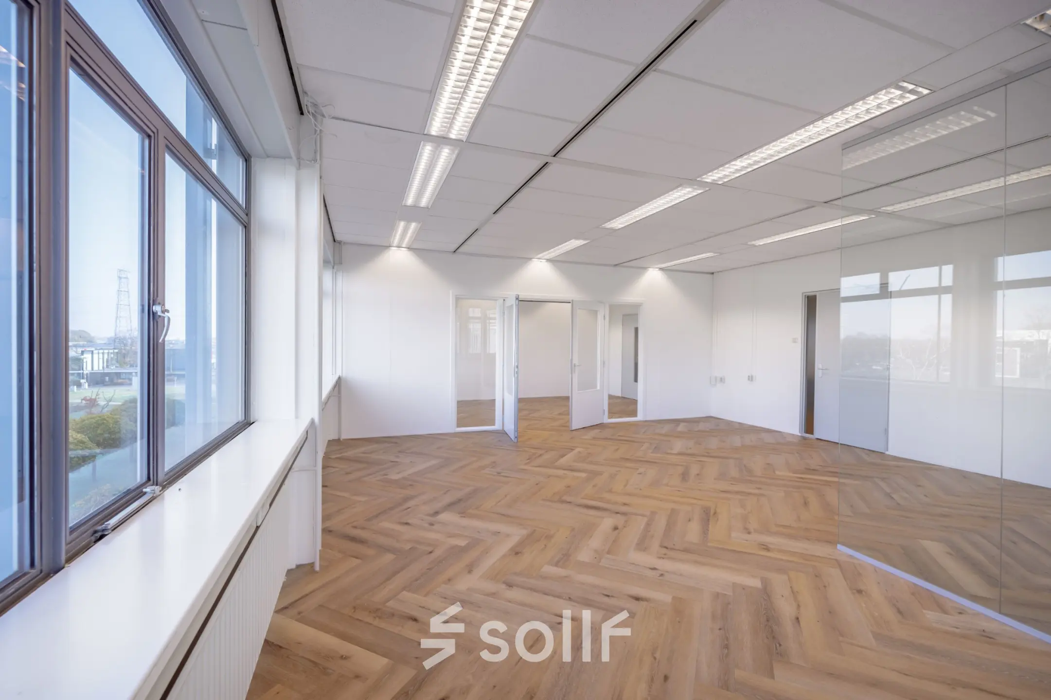 Spacious, well-lit office with herringbone flooring and large windows, available for office space rental on Oude Apeldoornseweg 41-45, Apeldoorn.