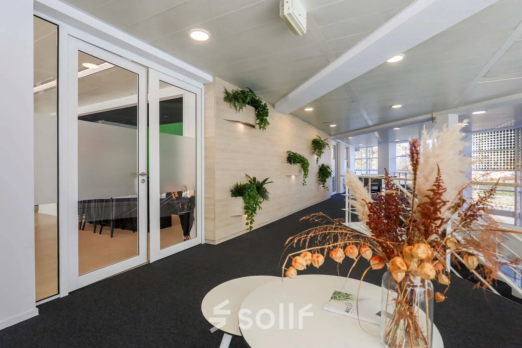Modern office space for rent in Apeldoorn with elegant furnishings, featuring a glass-enclosed area and tasteful decor.