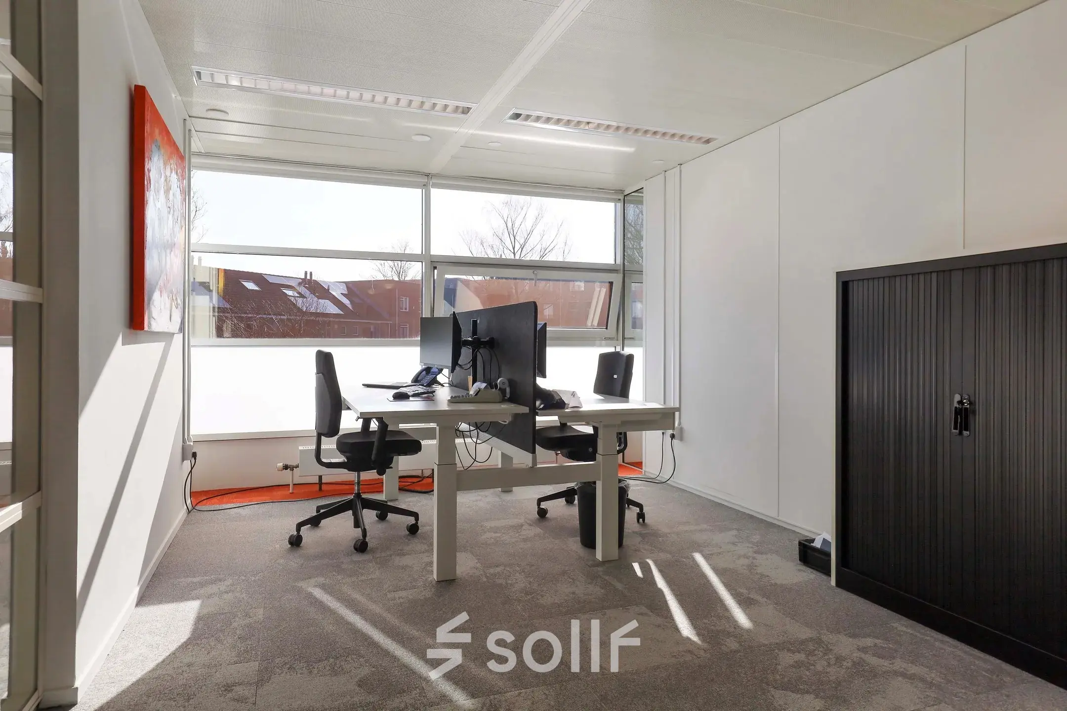 Bright office space with two desks, chairs, and a large window at Prins Willem-Alexanderlaan 301, ideal for office space rental in Apeldoorn.