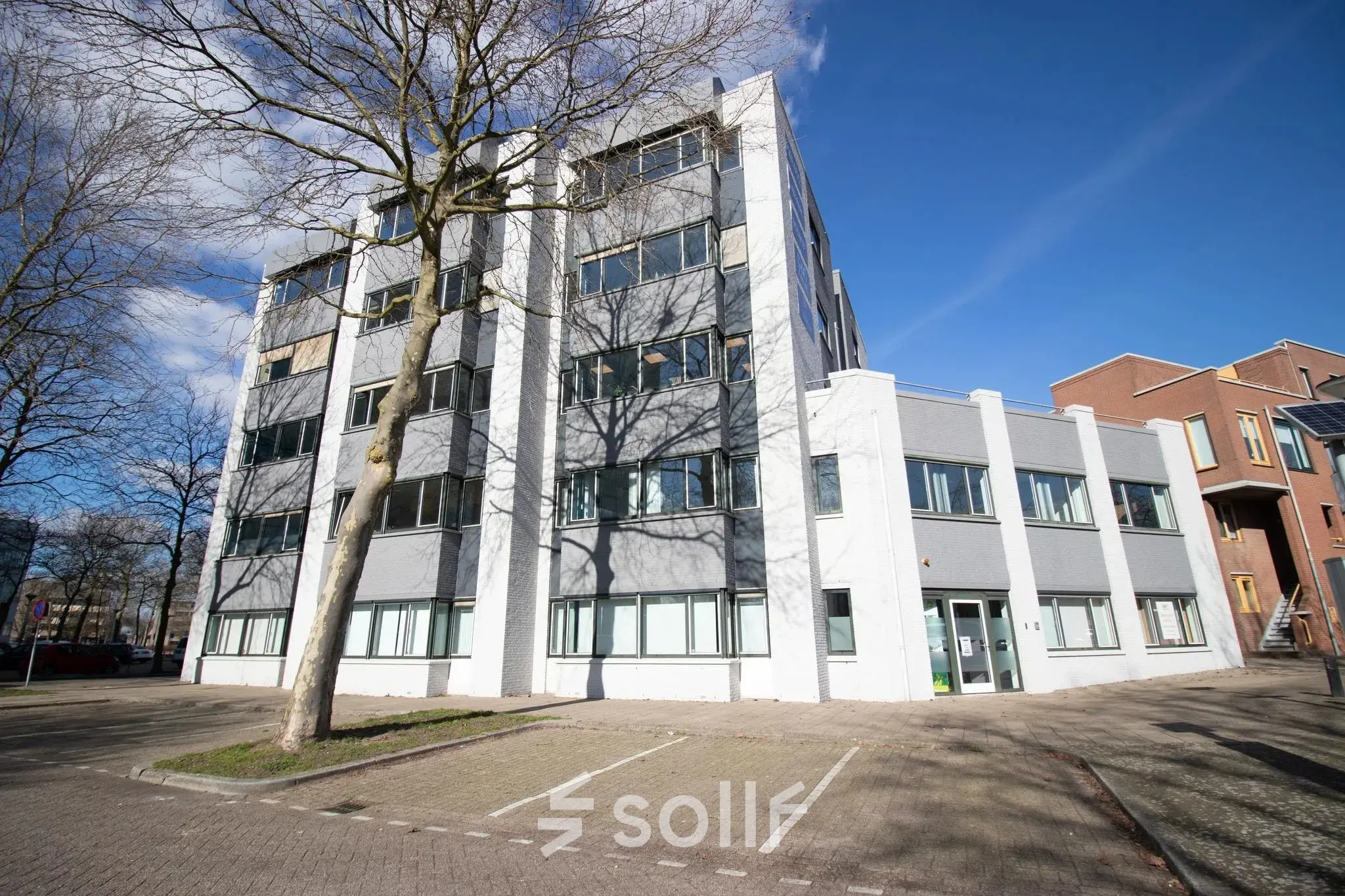 Exterior view of an office building at Prins Willem-Alexanderlaan 401, Apeldoorn, ideal for those seeking office space rental. Features a modern facade with adjacent parking spaces.