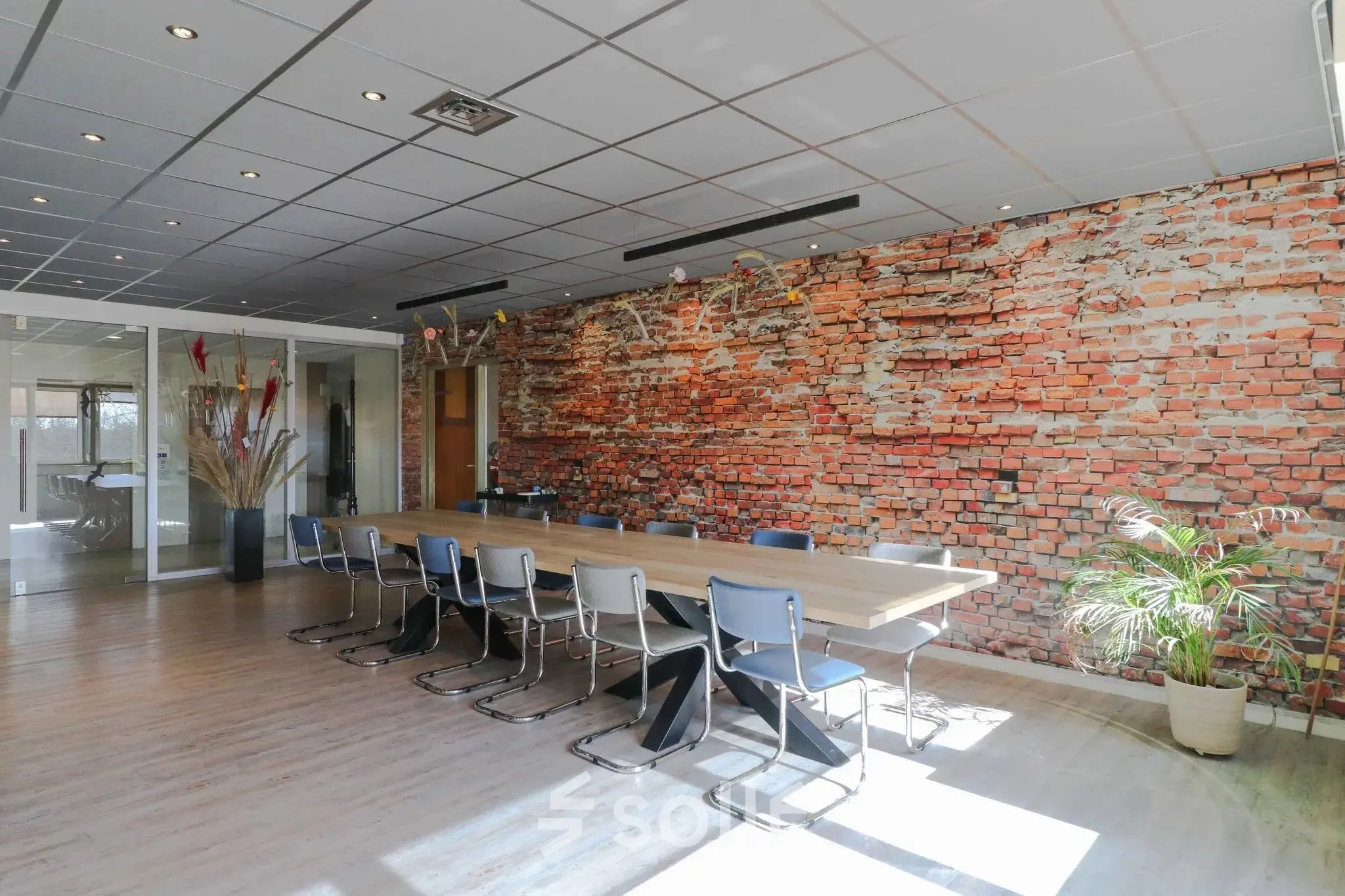 Spacious meeting room at Prins Willem-Alexanderlaan 401, Apeldoorn, featuring a long wooden table with chairs and a striking brick accent wall, available for office space rental.