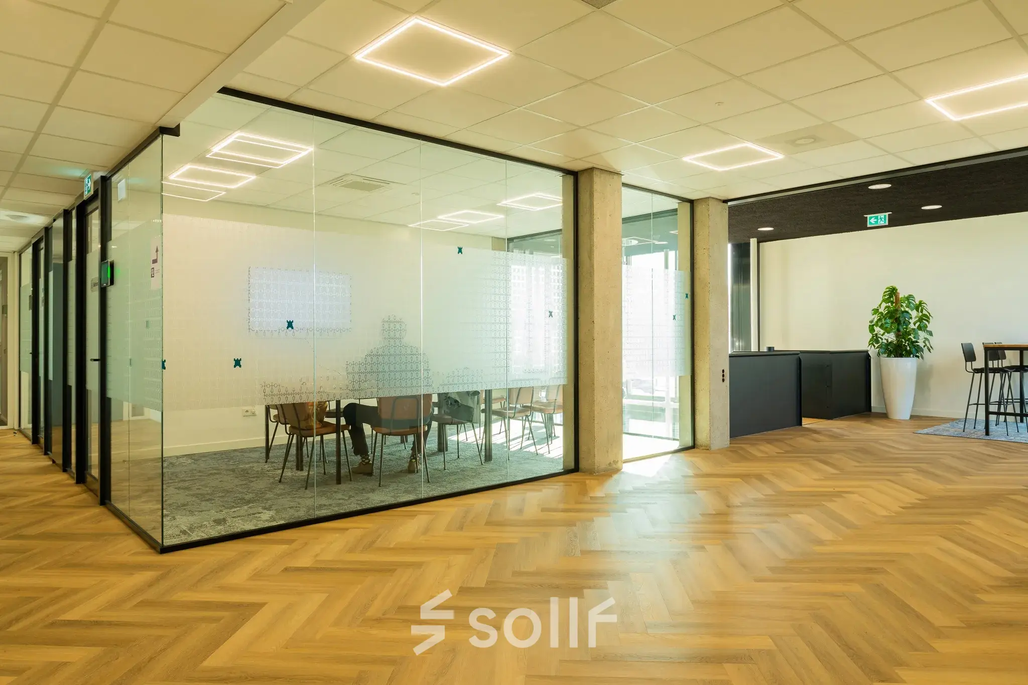 Interior view of an office space to rent at Prins Willem Alexanderlaan 701, Apeldoorn, featuring a glass-walled conference room and furnished with modern chairs and tables.