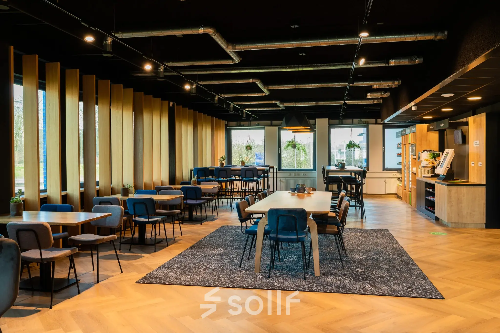 Spacious, modern office to rent at Prins Willem Alexanderlaan 701, Apeldoorn, featuring stylish furnishings, wood accents, and abundant natural light ideal for collaborative activities.