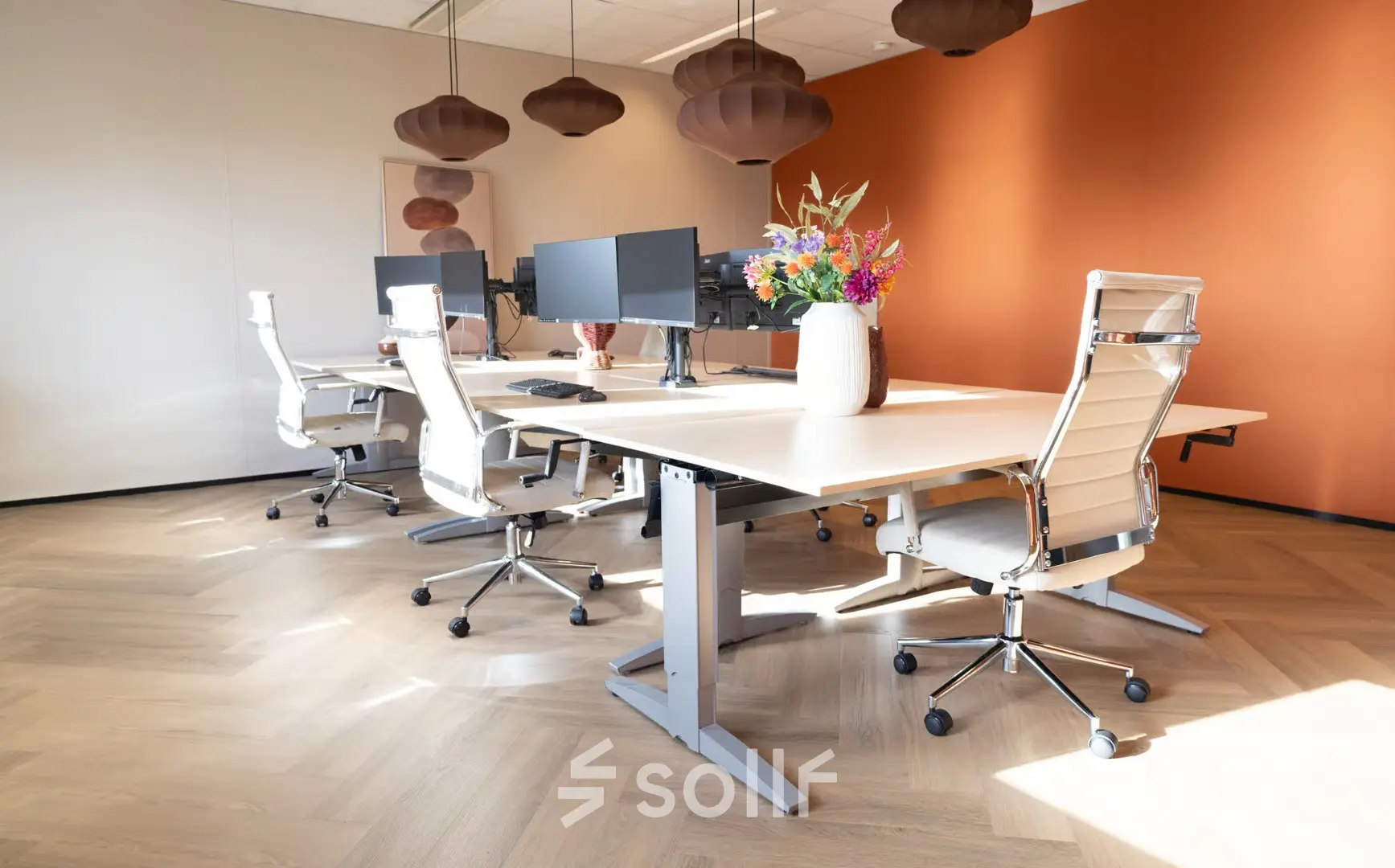 Bright office space at Schumanpark 9, Apeldoorn, featuring modern desks and chairs with a vibrant vase of flowers. Ideal for office space rental.