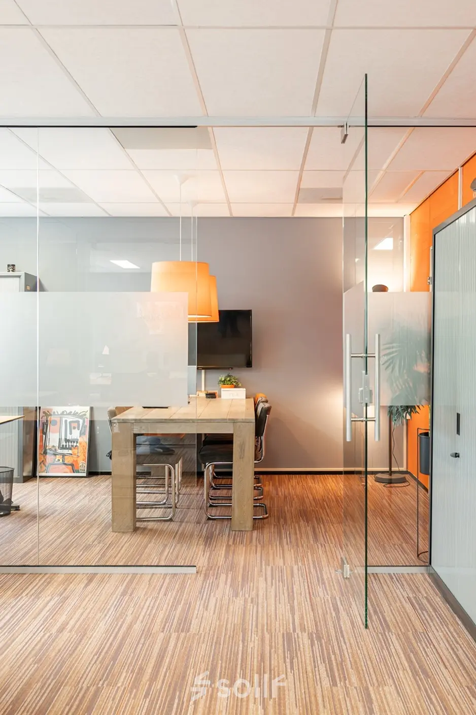 Modern office space to rent at Vlamoven 34, Arnhem IJsseloord, featuring a stylish meeting area with glass walls and warm lighting.