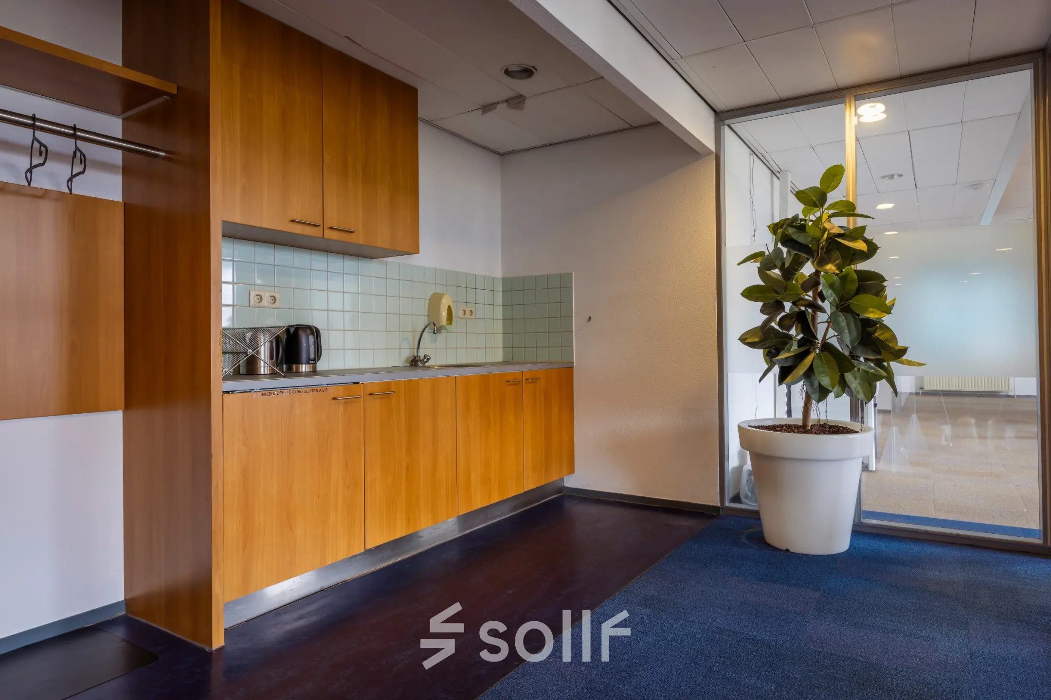 Office space at Kronenburgsingel 525 in Arnhem Zuid with a kitchenette area featuring wooden cabinets, a coffee maker, and a potted plant, ideal for office space rental.