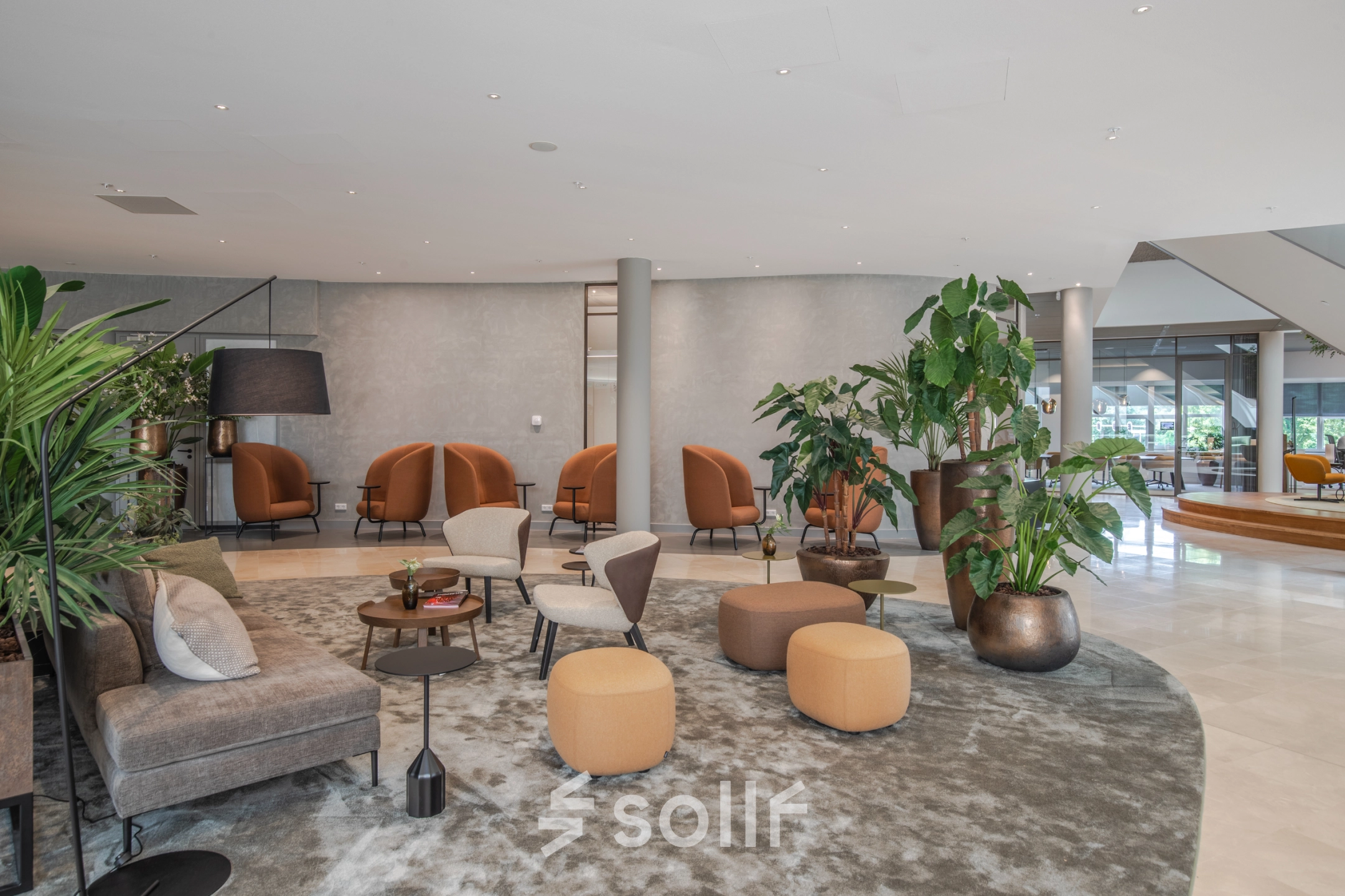 Stylish lounge area in Arnhem Zuid with modern seating and lush plants, ideal for office space rental.