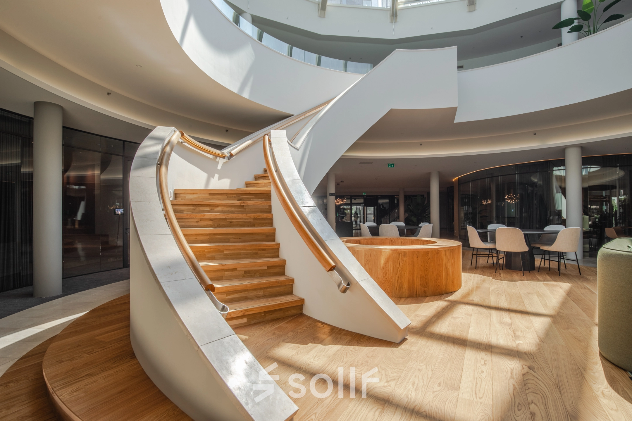 Bright and modern office space with a stylish wooden staircase and seating area, ideal for office space rental in Arnhem Zuid.