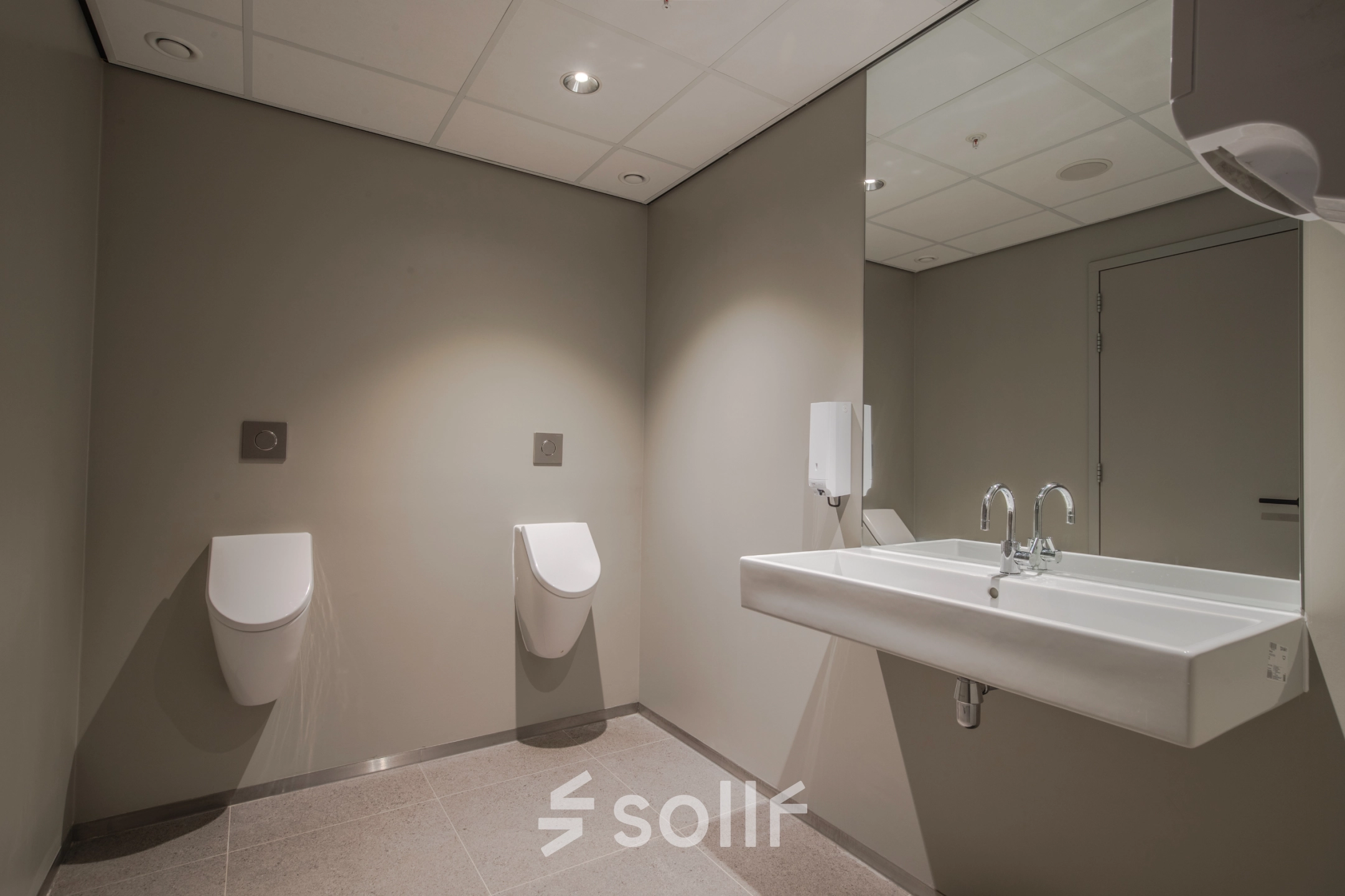 Public restroom with two urinals and a large white sink, ideal for businesses seeking office space rental at Rijksweg-West 2 in Arnhem Zuid.