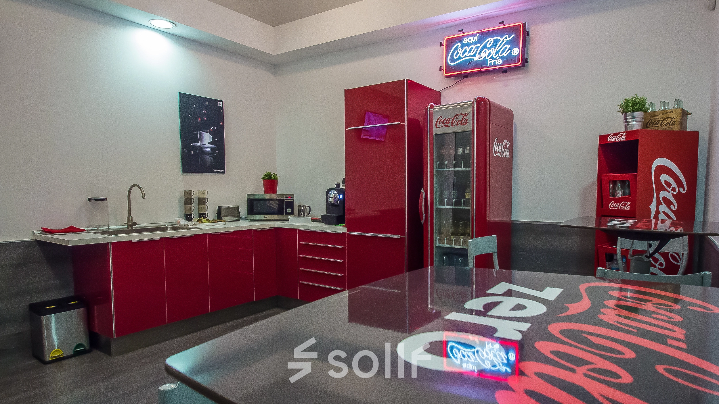 Bright kitchen area in an office space rental with red cabinets and Coca-Cola branding, located at Carrer d'Aribau 161 in Barcelona Eixample.