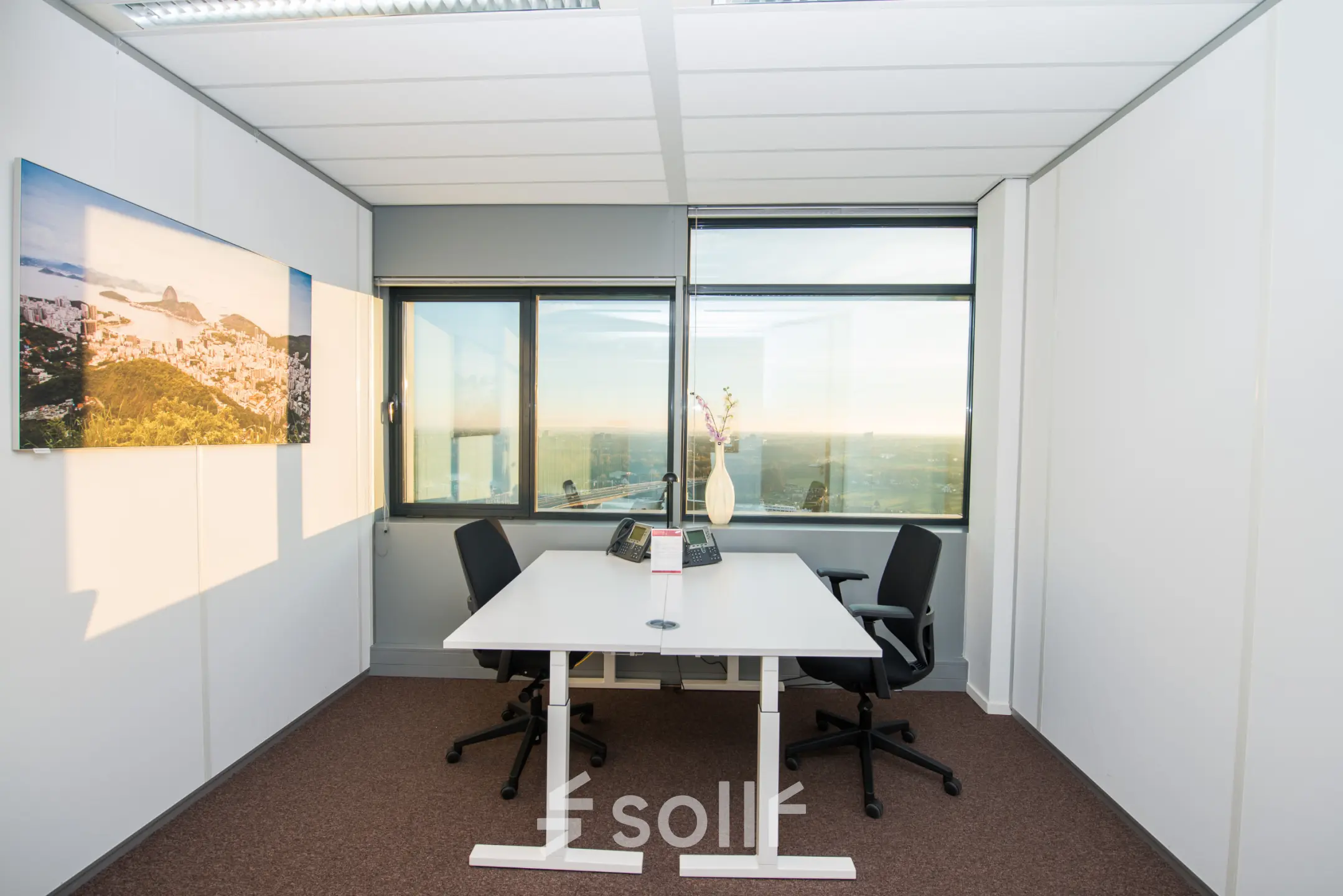 Interior office space for rent at Carrer de la Marina 16-18, Barcelona Sant Martí, featuring a desk, chairs, and large windows offering city views.