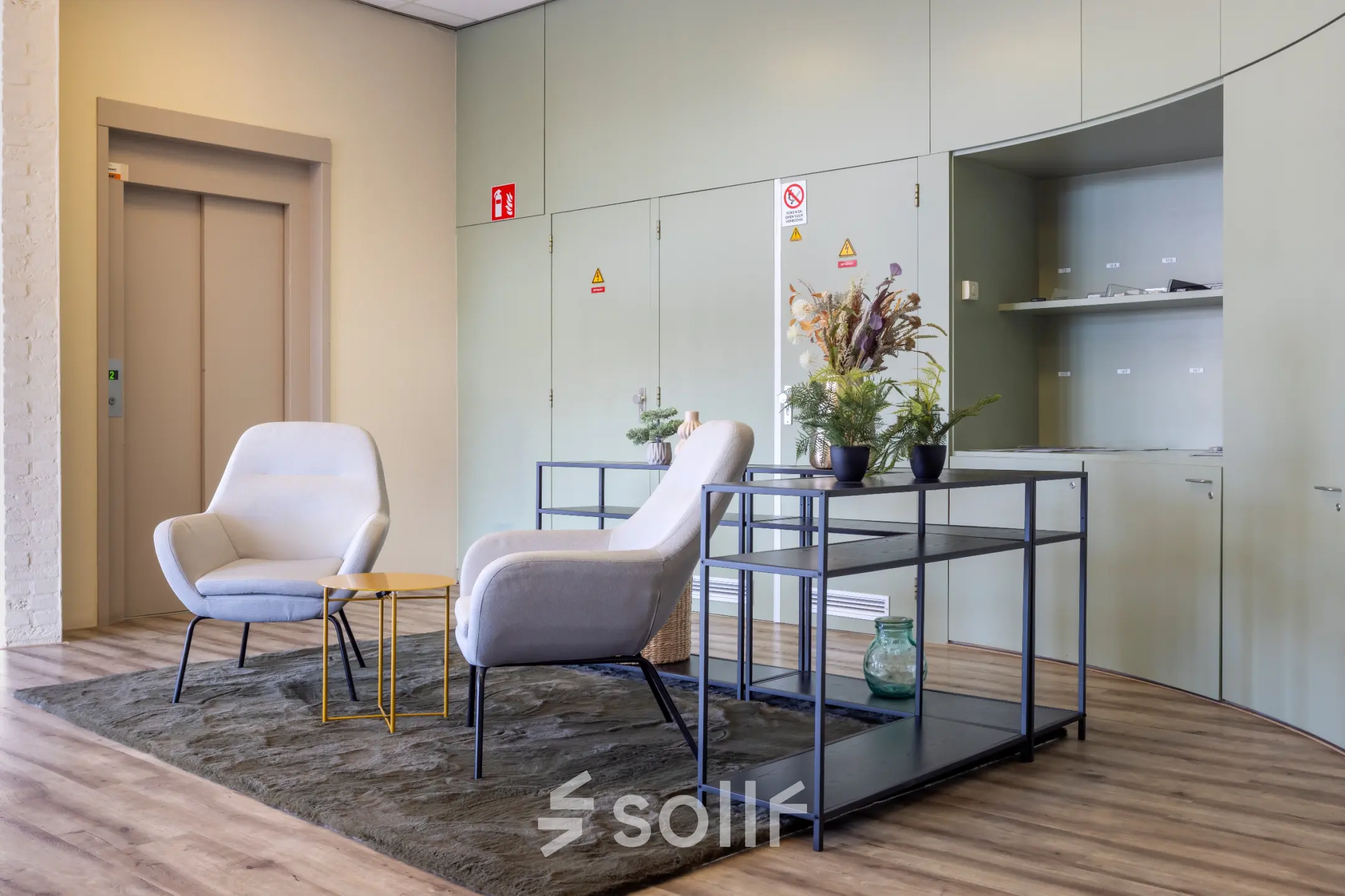 Furnished office space with modern chairs, a small table, and decorative plants near an elevator at Kamerlingh Onnesweg 10, Barendrecht. Ideal for office space rental.
