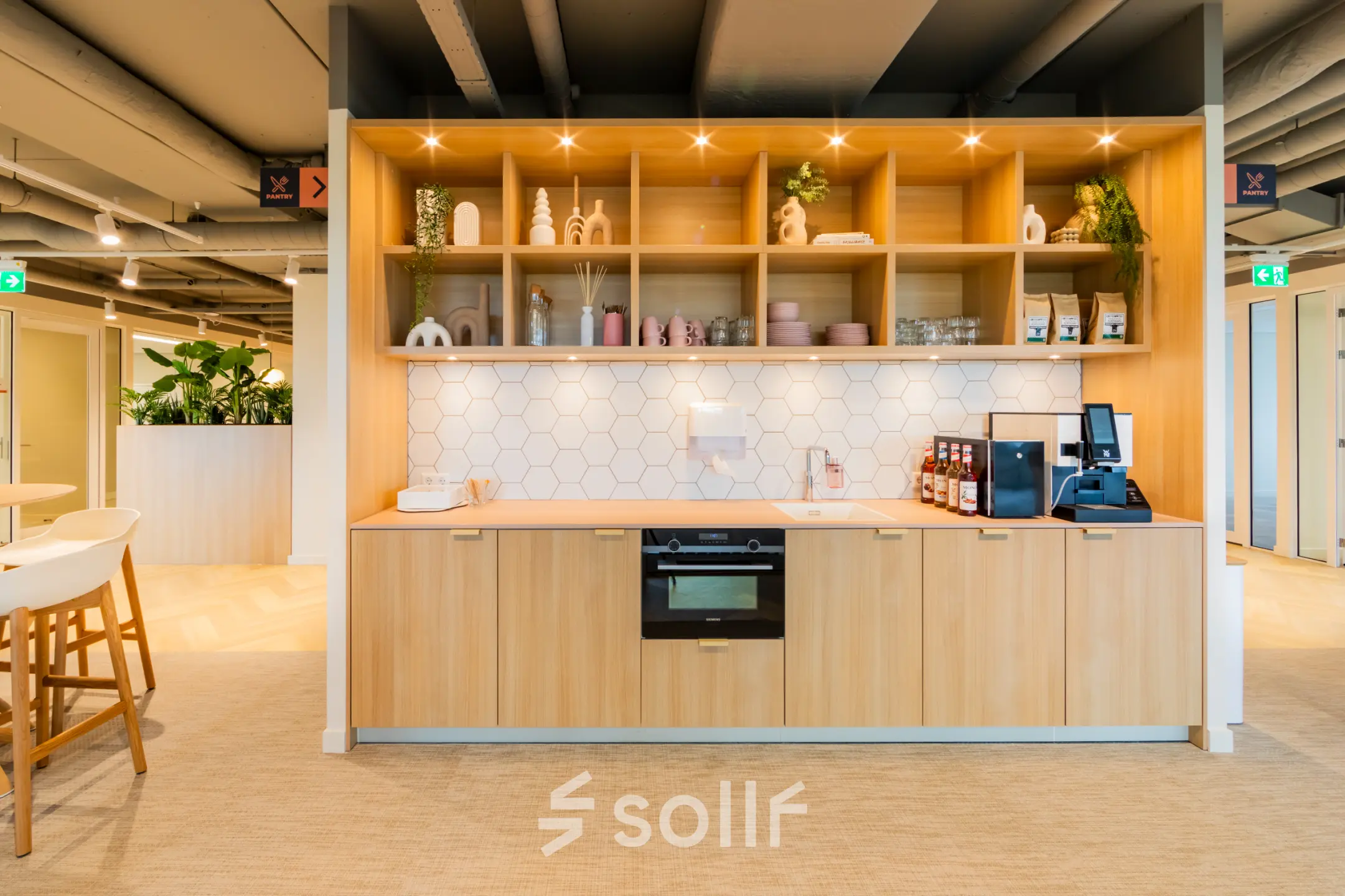 Bright office pantry with wooden cabinetry, coffee machine, and decorative shelves offering comfortable office space rental at Baron van Nagellstraat 136, Barneveld.
