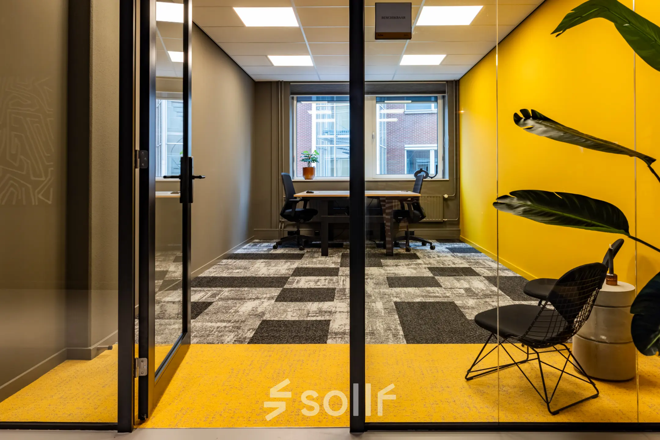 Bright office space at Baron van Nagellstraat 136, Barneveld, showcasing minimalist furnishings and a vibrant yellow accent wall, ideal for office space rental.
