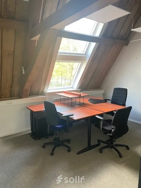 Bright office to rent at Blokstallen 2B, Bergen op Zoom, featuring wooden beams and desks beneath a large skylight, ideal for business activities.