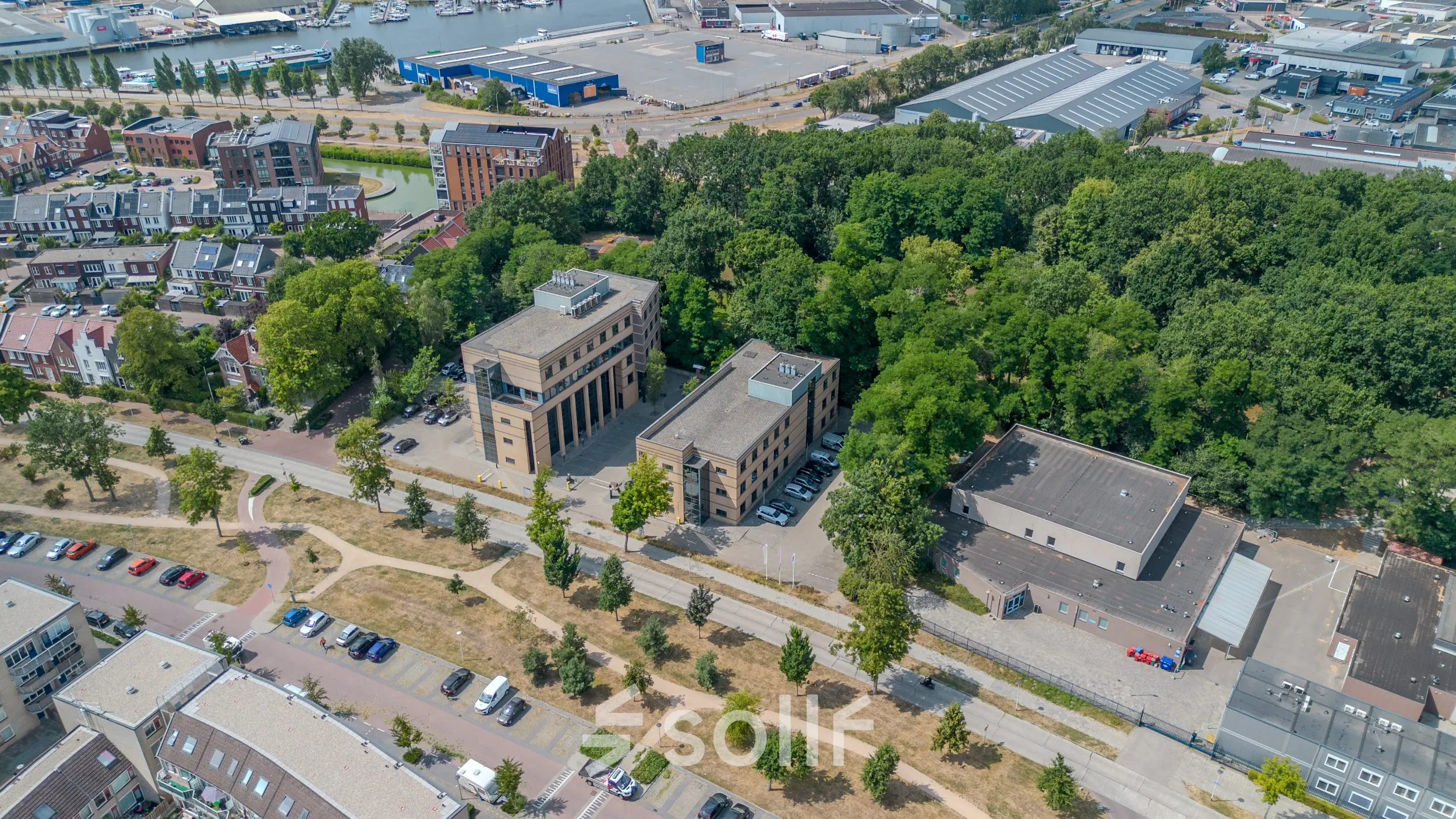 Aerial view of office buildings for rent at Rijtuigweg 10, Bergen op Zoom, surrounded by greenery and near a waterway, offering potential office space rental opportunities.