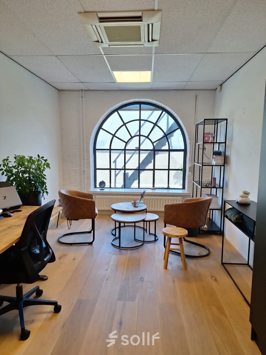 Bright office space at Zuidzijde Haven 39a, Bergen op Zoom, featuring a large arched window, wooden flooring, and modern furnishings, ideal for office space rental.