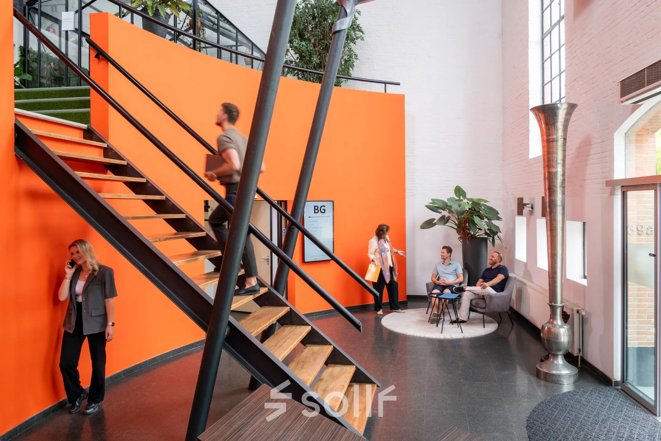 Bright office space with modern staircase at Zuidzijde Haven 39a, featuring professionals conversing and using devices. Ideal for rent office space seekers.