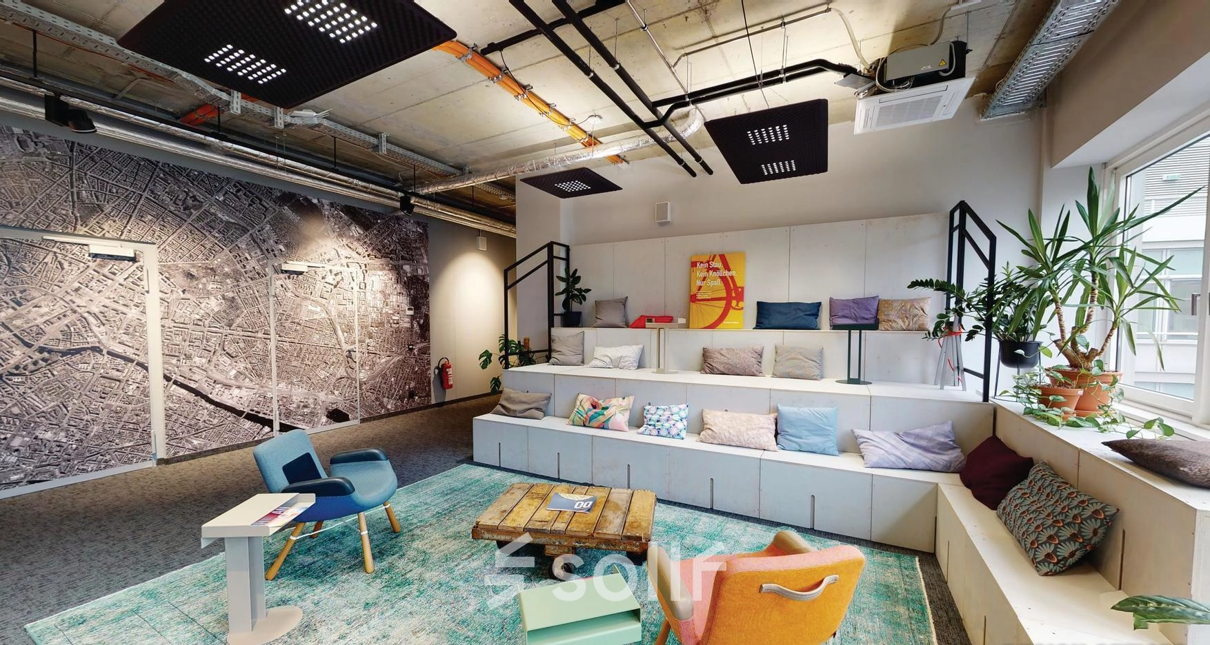 Furnished office space at Koppenstraße 93 in Berlin Friedrichshain, featuring vibrant seating and a large map wall for creative meetings and collaboration.