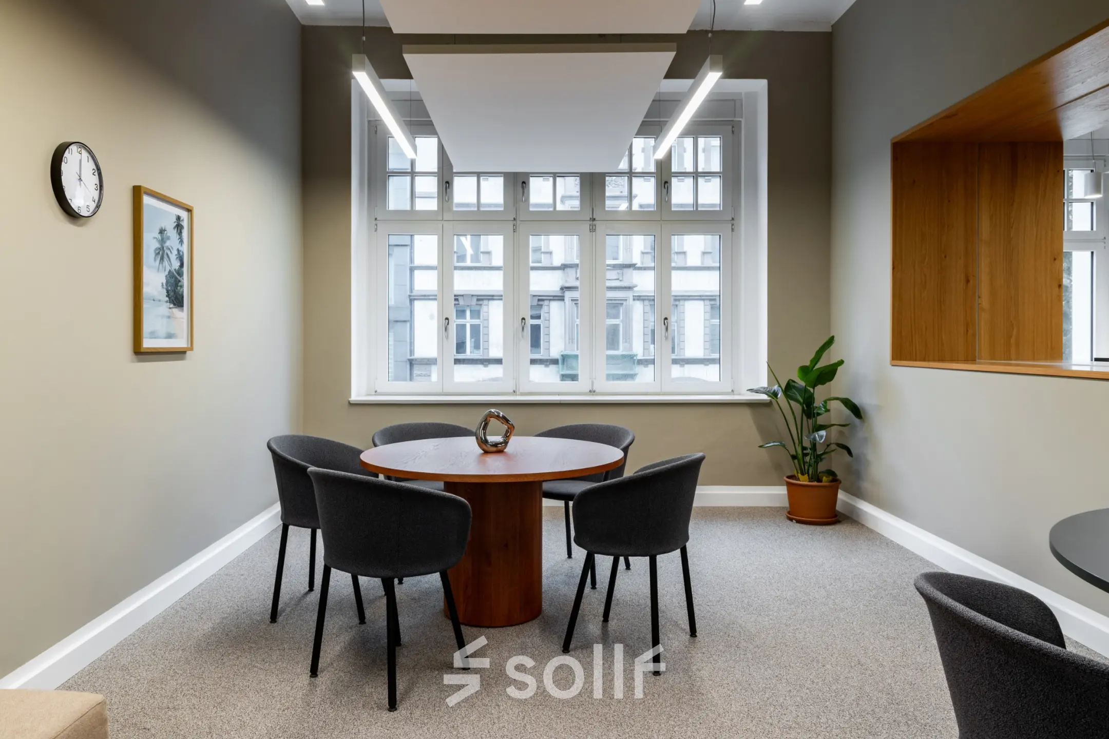 Bright office space for rent at Chausseestraße 29, Berlin Kreuzberg, featuring a round table with chairs beneath modern lighting, suitable for team meetings.